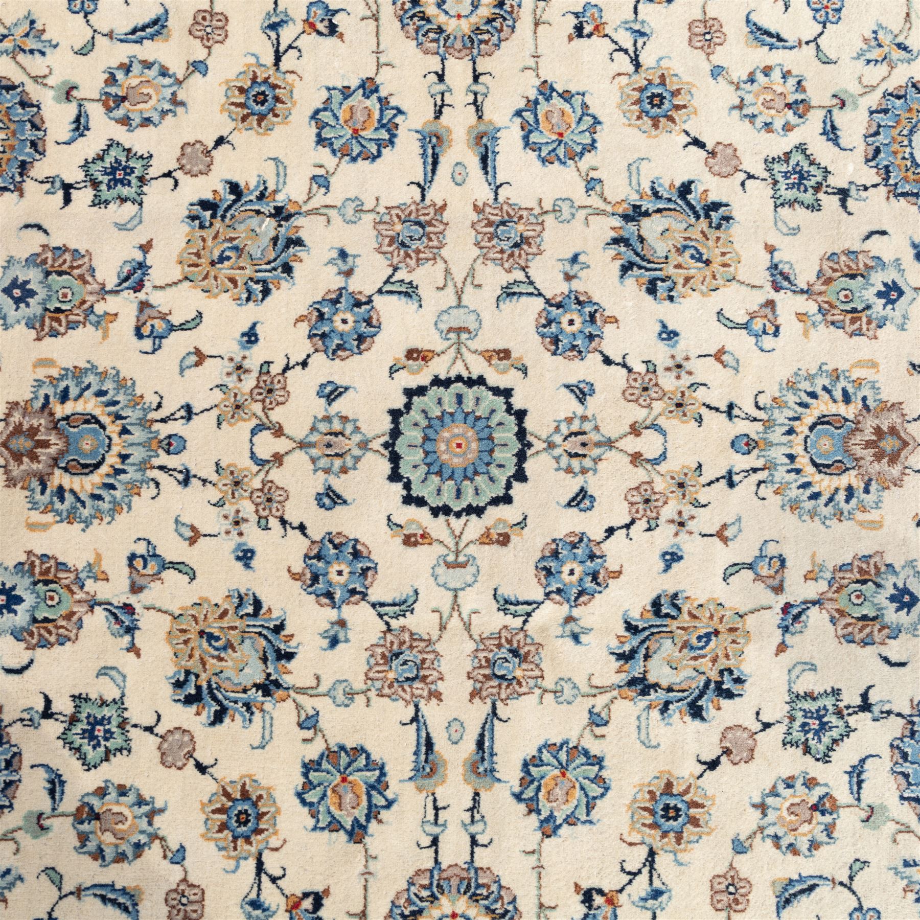 Large Central Persian Kashan hand-knotted carpet, ivory field with small central floral medallion issuing an all-over design of palmettes, rosettes, and scrolling vines enclosed by a complimentary foliate border framed by guard stripes, in a palette of ivory, power blues, and muted polychrome tones, with cotton fringe ends 