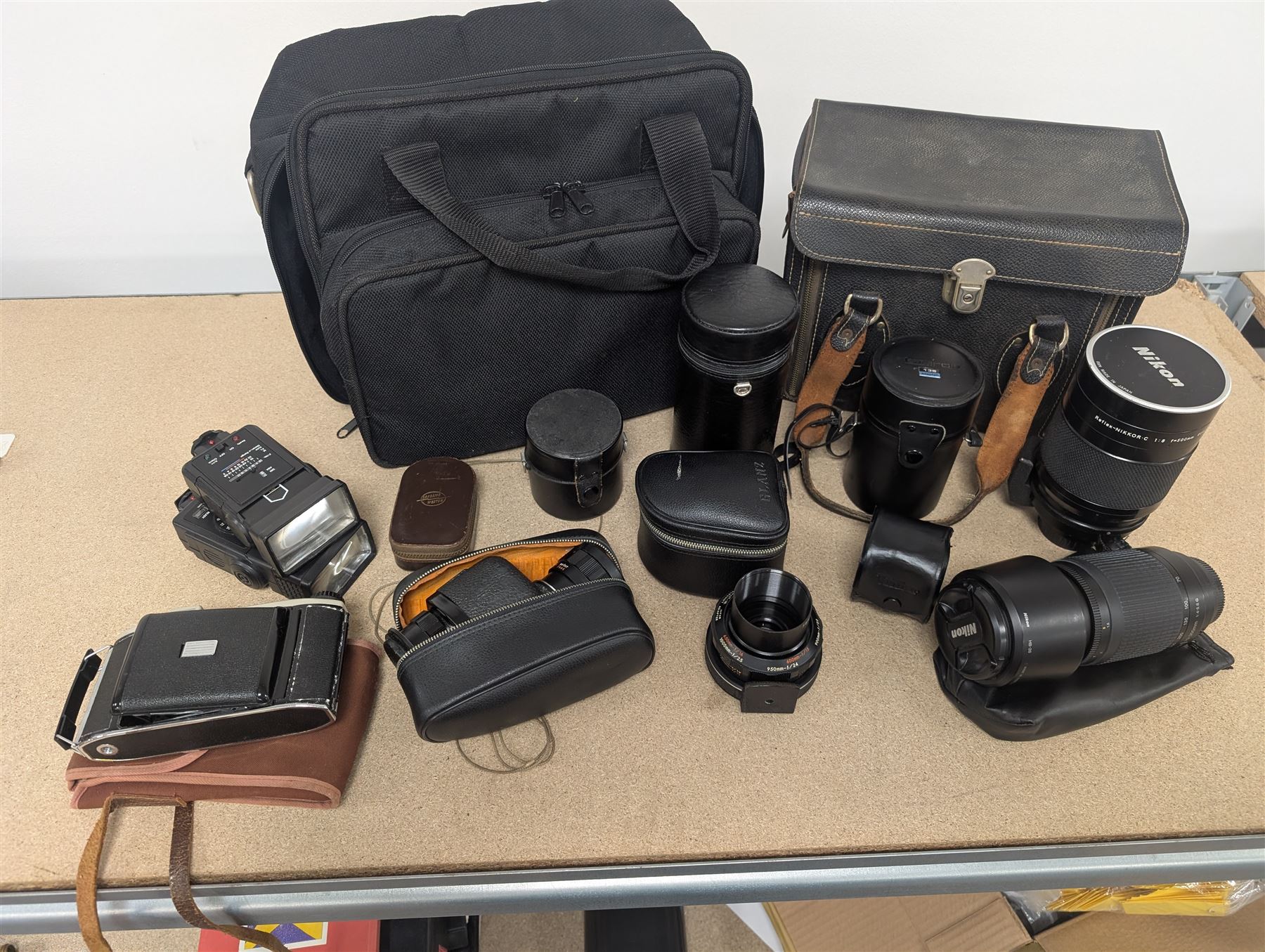 Kodak Dakon II folding camera and a collection of camera lenses and accessories, including Reflex-Nikkor  1:8 f=500mm, NikoN AF Nikkor 70-300mm 1:4-5.6G, Micro TM monocular lens and Teleshot adapter, two cases, Weston exposure meter, two cases etc