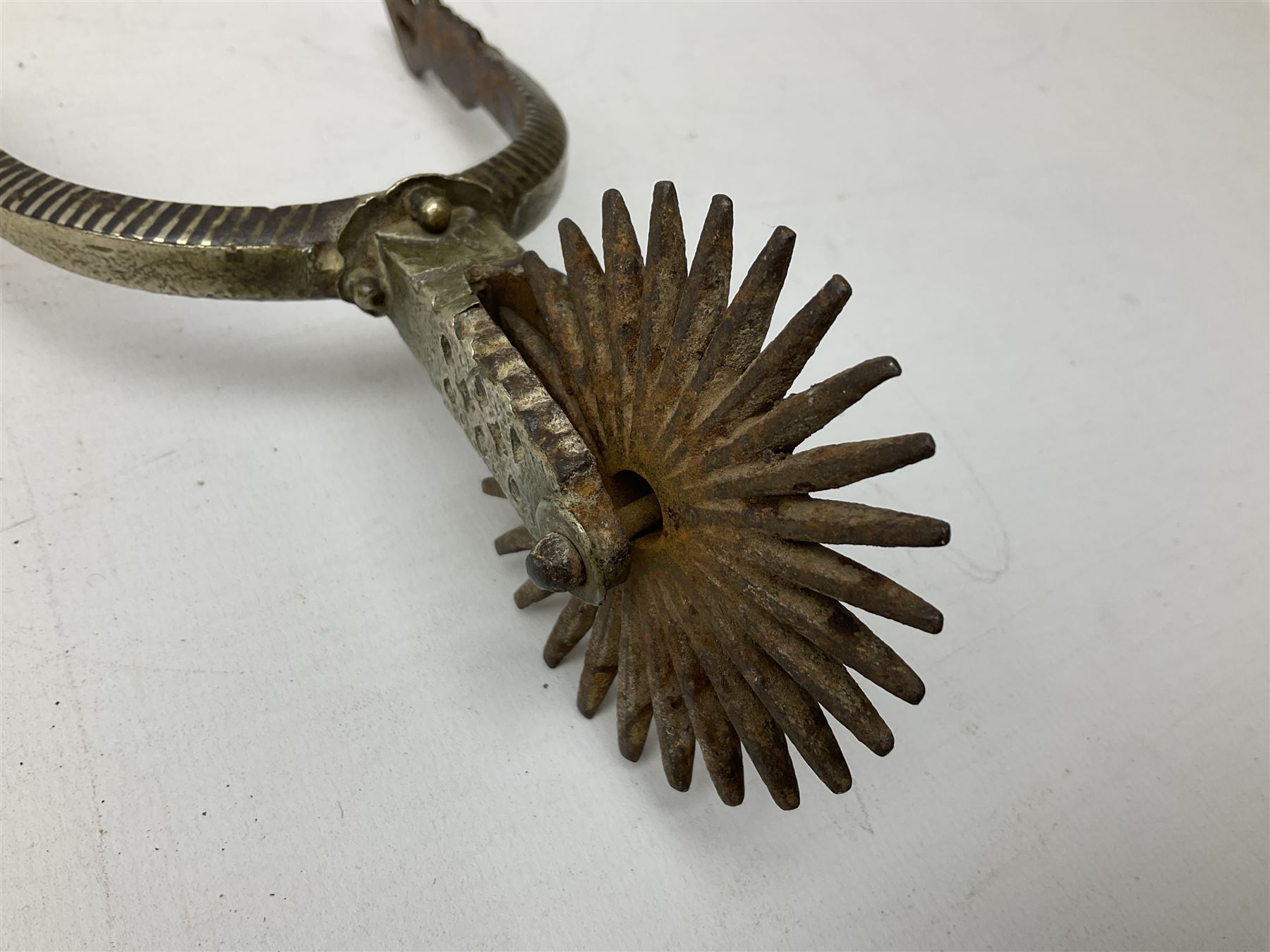 Pair of late 19th century South American iron spurs, engraved silver mounts, with sunburst rowls