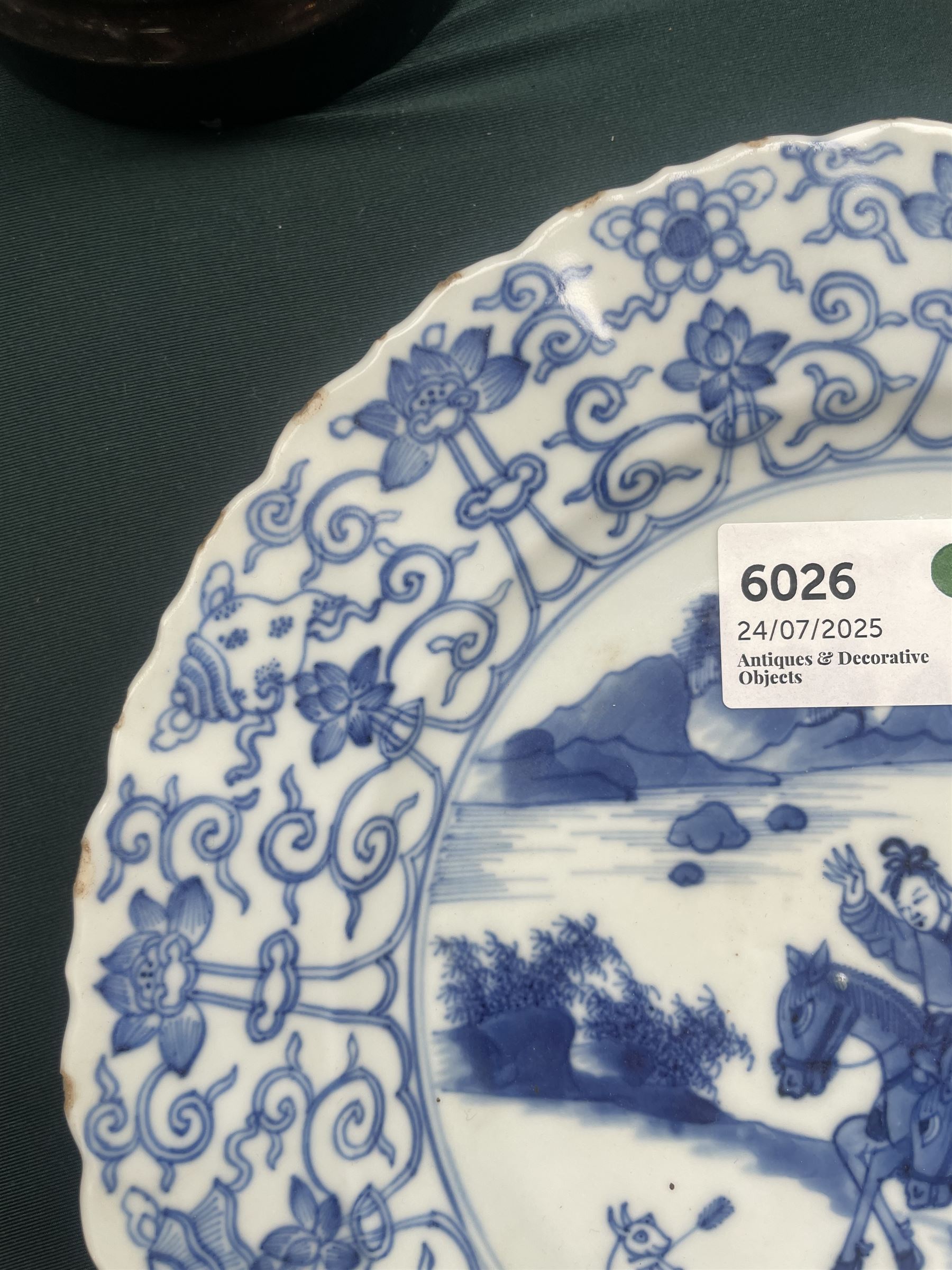 Chinese Kangxi style blue and white plate, decorated to the centre with a hunting scene  of two hunters on horse back, surrounded by a foliate boarder, with with six character double ring mark beneath