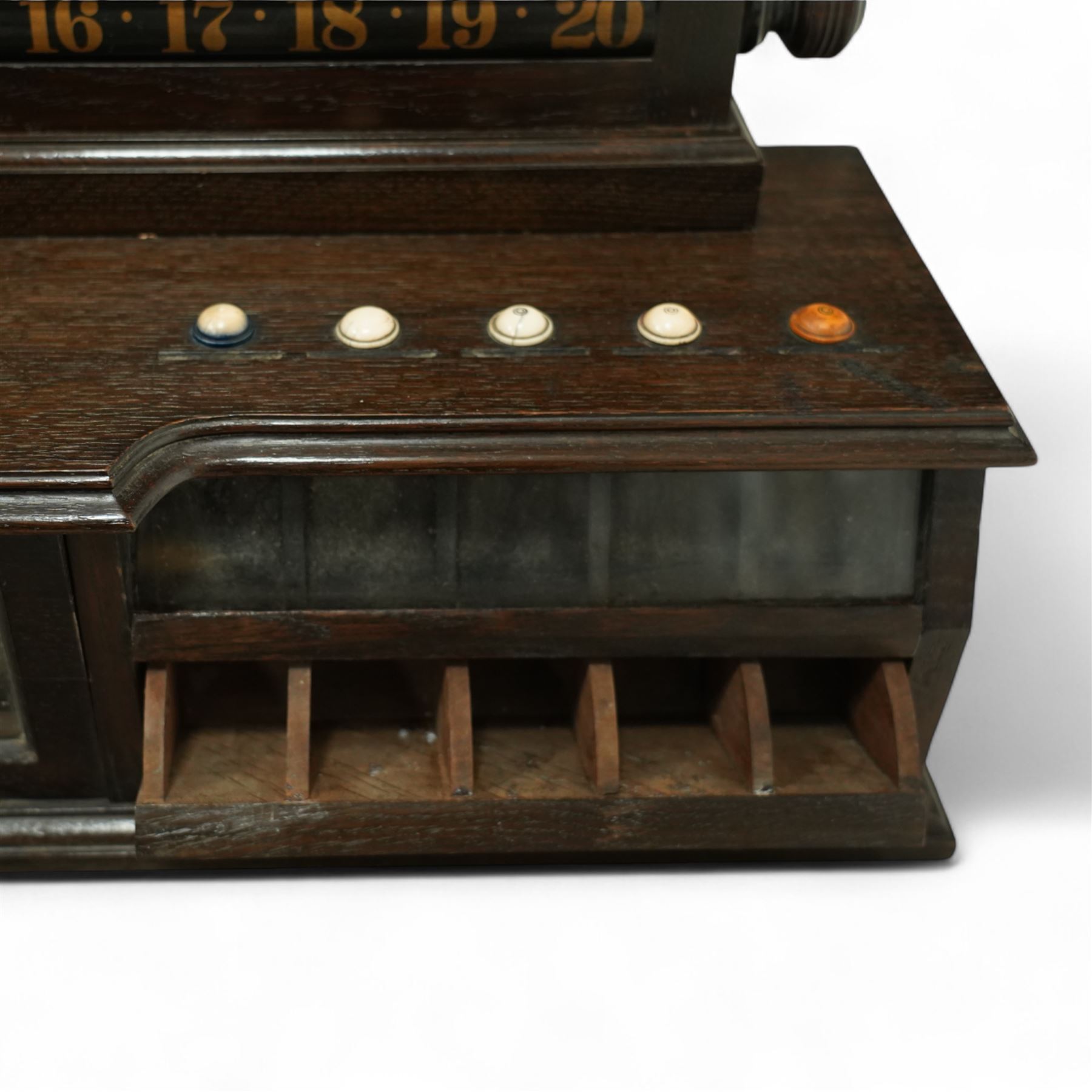 Victorian wall-mounted oak and walnut cased scoreboard,  moulded top, with a name stencilled in the frieze ‘J. Ashcroft, Victoria Street, Liverpool’, the board with chalk panel in the centre for recording scores, sliding panels on both sides for the various games of Billiards and Snooker, two numbered rotating arms with adjustable sliding score keepers, the base section with 5 apertures on each side, and coloured ivory roundels, all with glass front for viewing the tokens inside, with drawers beneath, the centre has a long glass panel for storing billiard balls, circa 1870 This item has been registered for sale under section 10 of the APHA Ivory Act Reference UNEGEBLB
