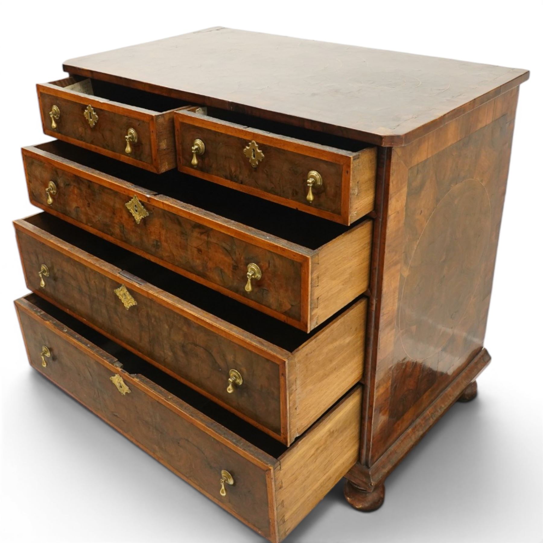 William & Mary period laburnum and walnut oyster-veneered chest, the rectangular top with canted corners and walnut banded edge, profusely decorated with oyster veneer and fruitwood stringing in concentric circles, fitted with two short over three long drawers with fruitwood banding, each fitted with original pressed brass escutcheons and pull handles, lower moulded edge over original bun feet