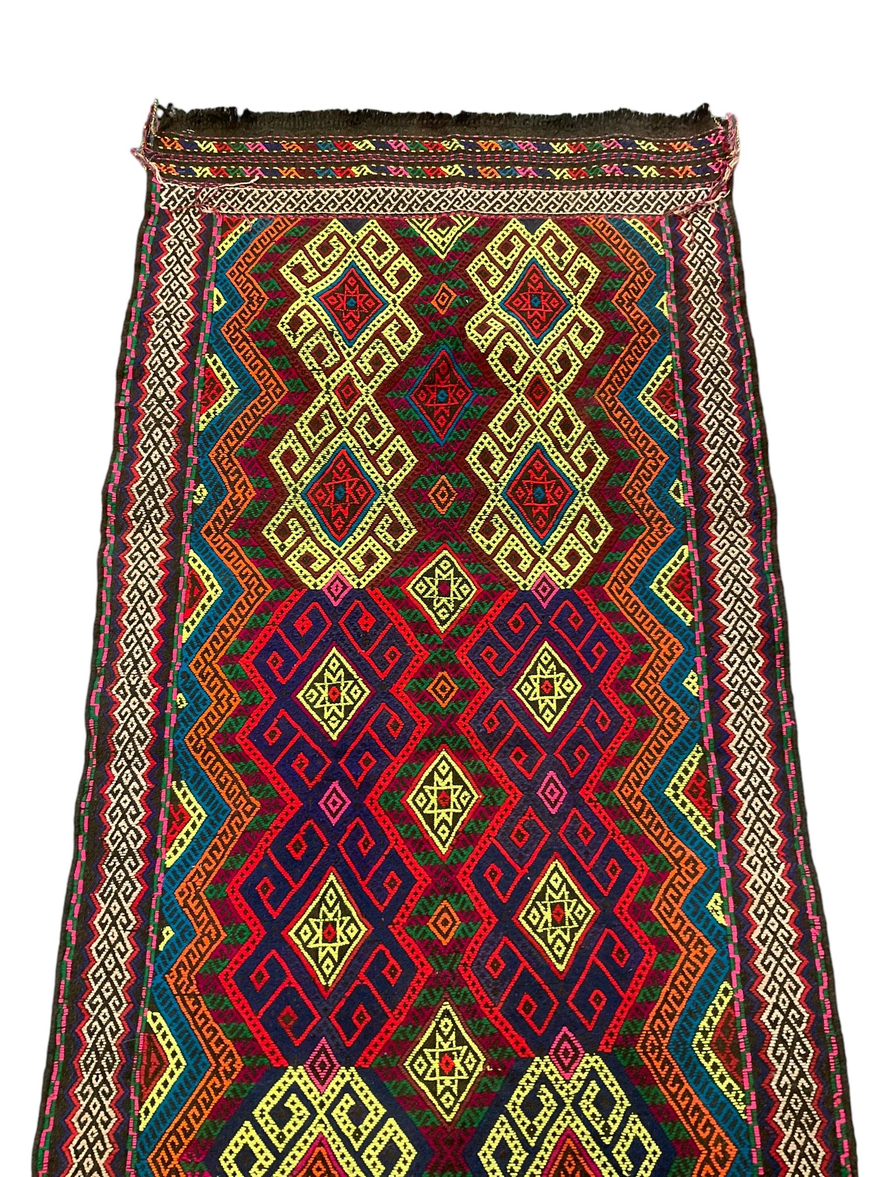 Flatweave geometric design rug, decorated with trailing hooked medallions within zig-zag bands, bright multi-coloured ground 