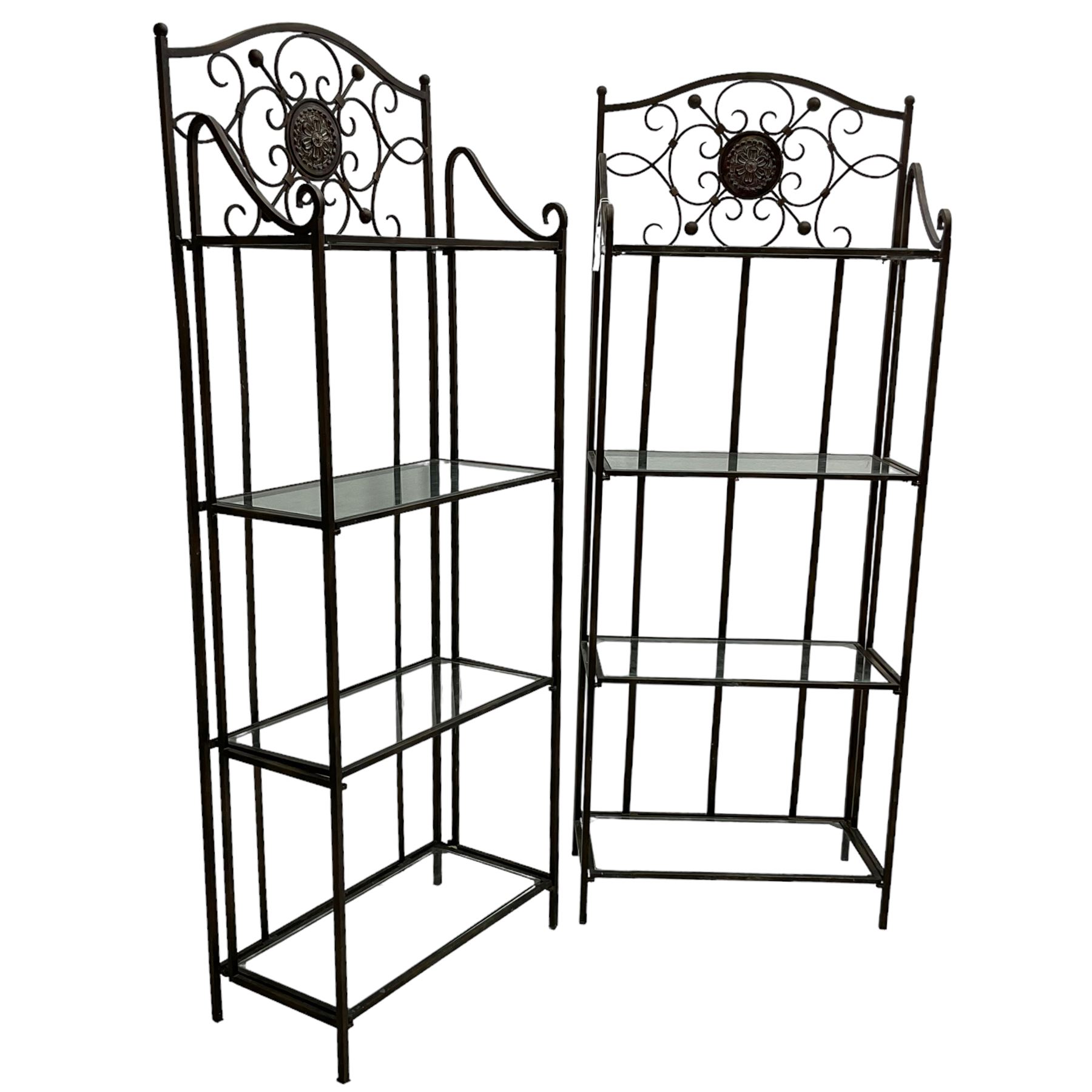 Pair of wrought metal conservatory plant stands, raised back with scrolling design, each fitted with three glass shelves