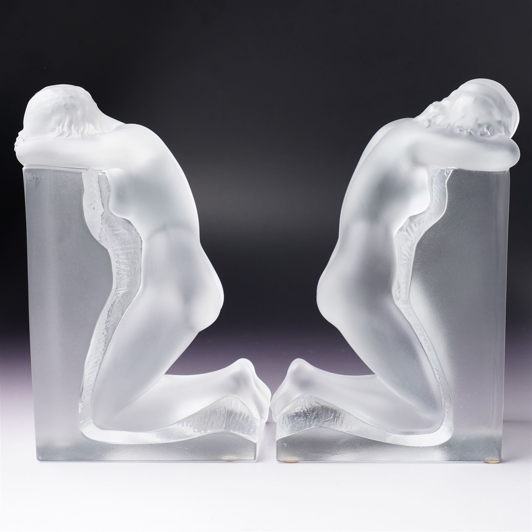 Pair of Lalique 'Reverie' glass bookends formed as two kneeling nude figures in clear and frosted glass inscribed 'Lalique France' to the plinth base H23cm