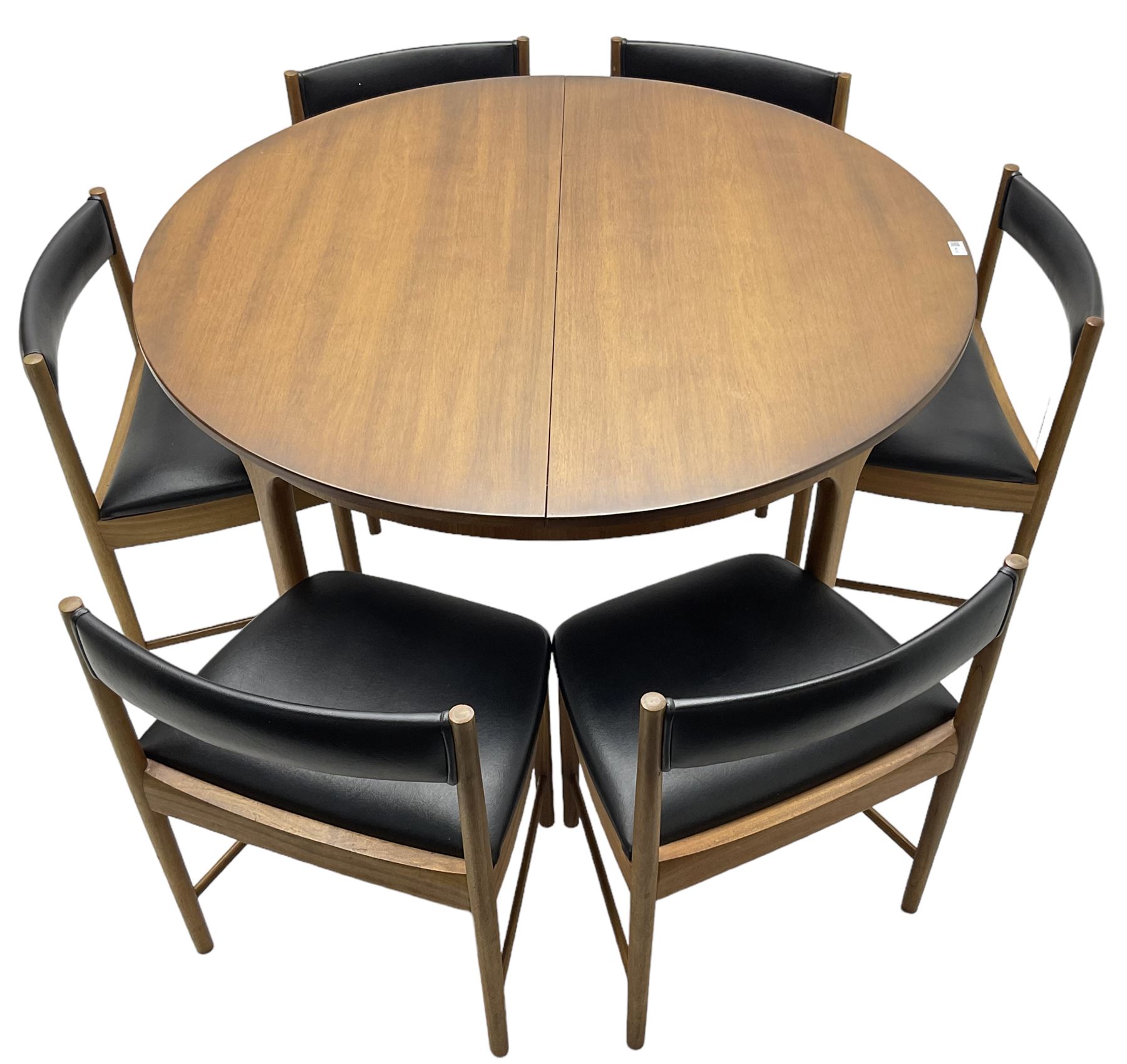 AH McIntosh & Co of Kirkaldy - mid-20th century teak extending dining table, circular top, concealed integrated double leaf, raised on tapered supports, label plaque to underside of leaf, together with a set of six chairs upholstered in black leatherette
