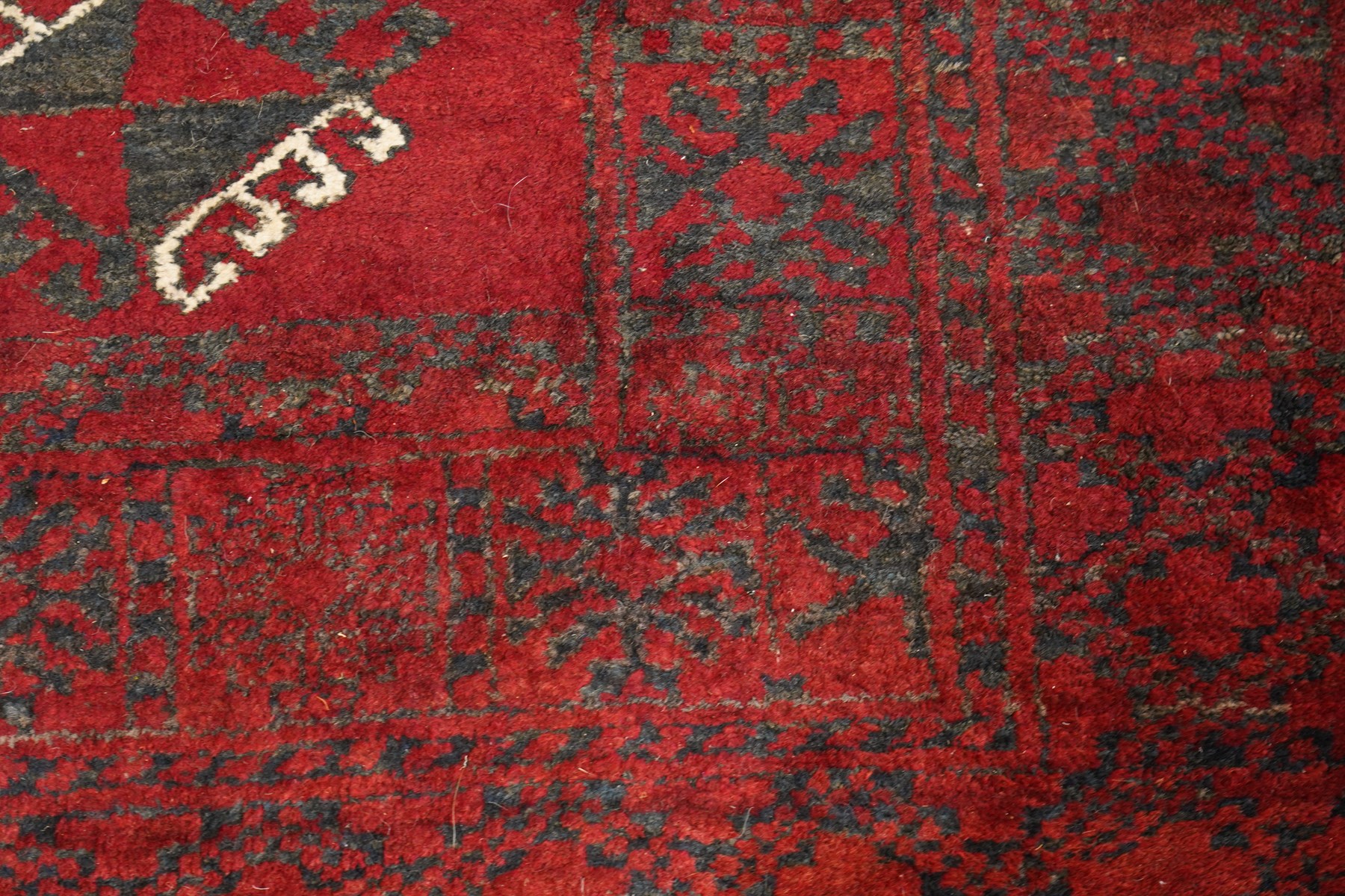 Afghan Turkoman crimson ground rug decorated with twin rows of hooked geometric guls within broad compartmented geometric borders (125cm x 201cm); Afghan Bokhara rug with repeated octagonal guls on a terracotta ground, enclosed by multiple geometric borders and patterned elem panels (120cm x 192cm) (2)