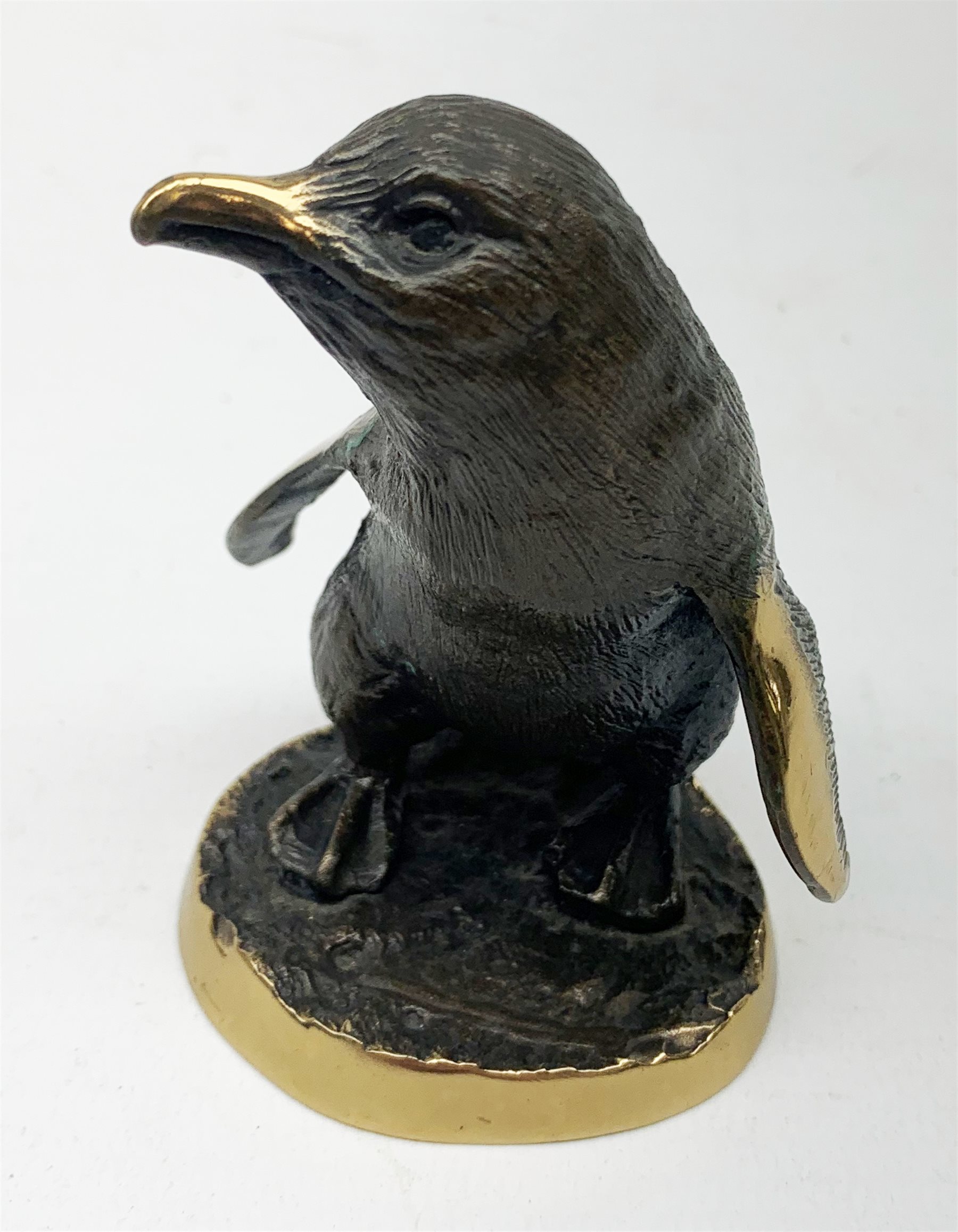 A cold painted model of a Kingfisher surmounted upon a branch surporting a small clear glass bowl, H10.5cm, together with a small bronze model of a penguin, stamped EWB, H7cm. 