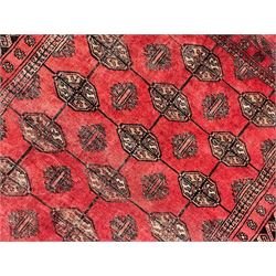 Afghan Bokhara red ground rug, the field decorated with three rows of Gul motifs, within multiple band borders decorated with trailing hook and geometric motifs 