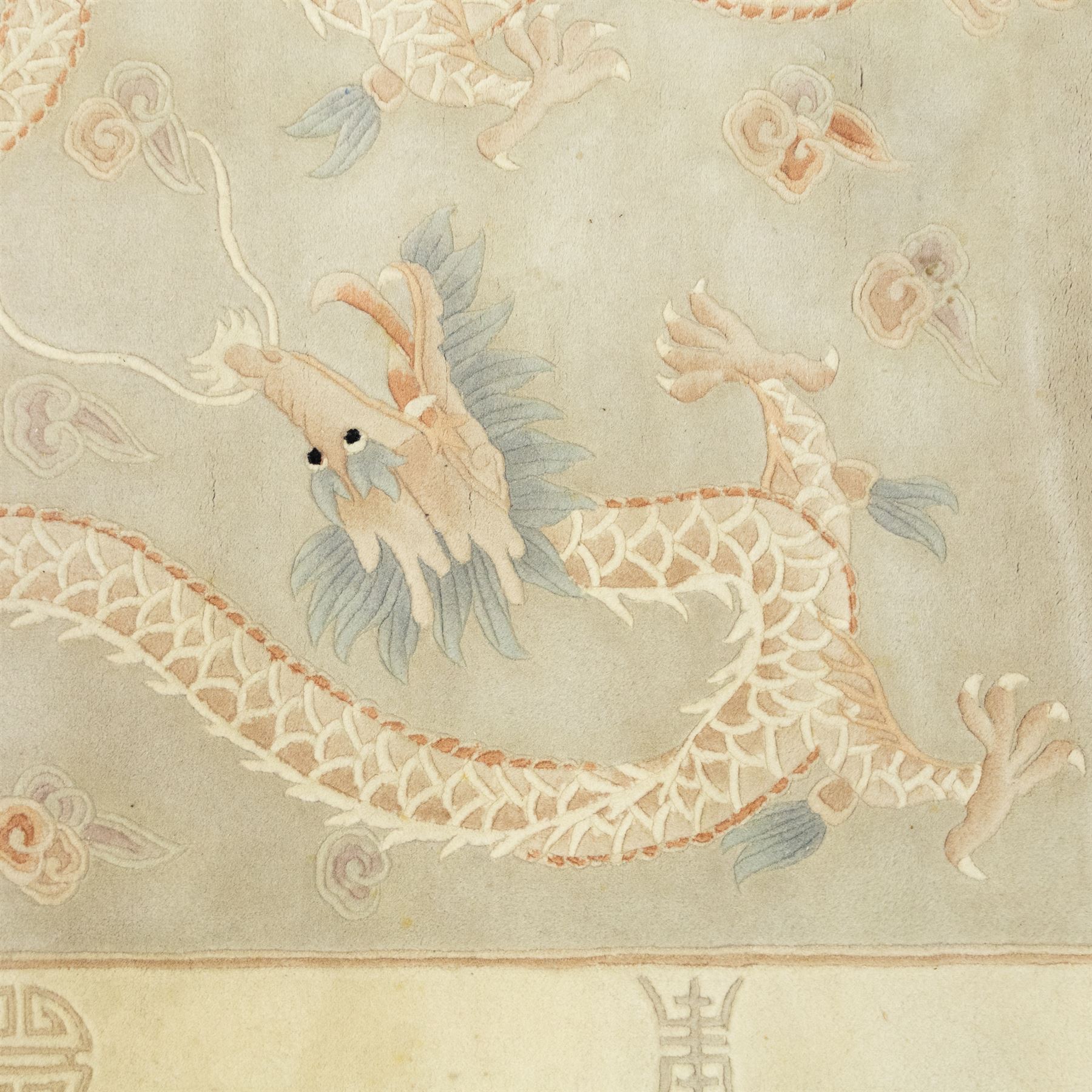 Chinese wool rug, the pale grey central field decorated with two stylised dragons, flaming pearls and cloud scrolls, within a cream border of shou medallions and geometric motifs, with cotton fringe ends