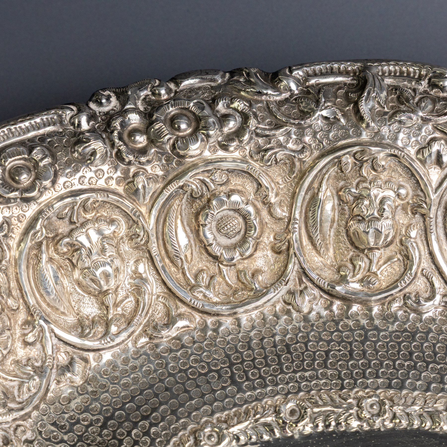 Late 19th/early 20th century continental silver serving bowl, of oval form, profusely embossed with scrolling floral and foliate decoration, with hammered finish to interior