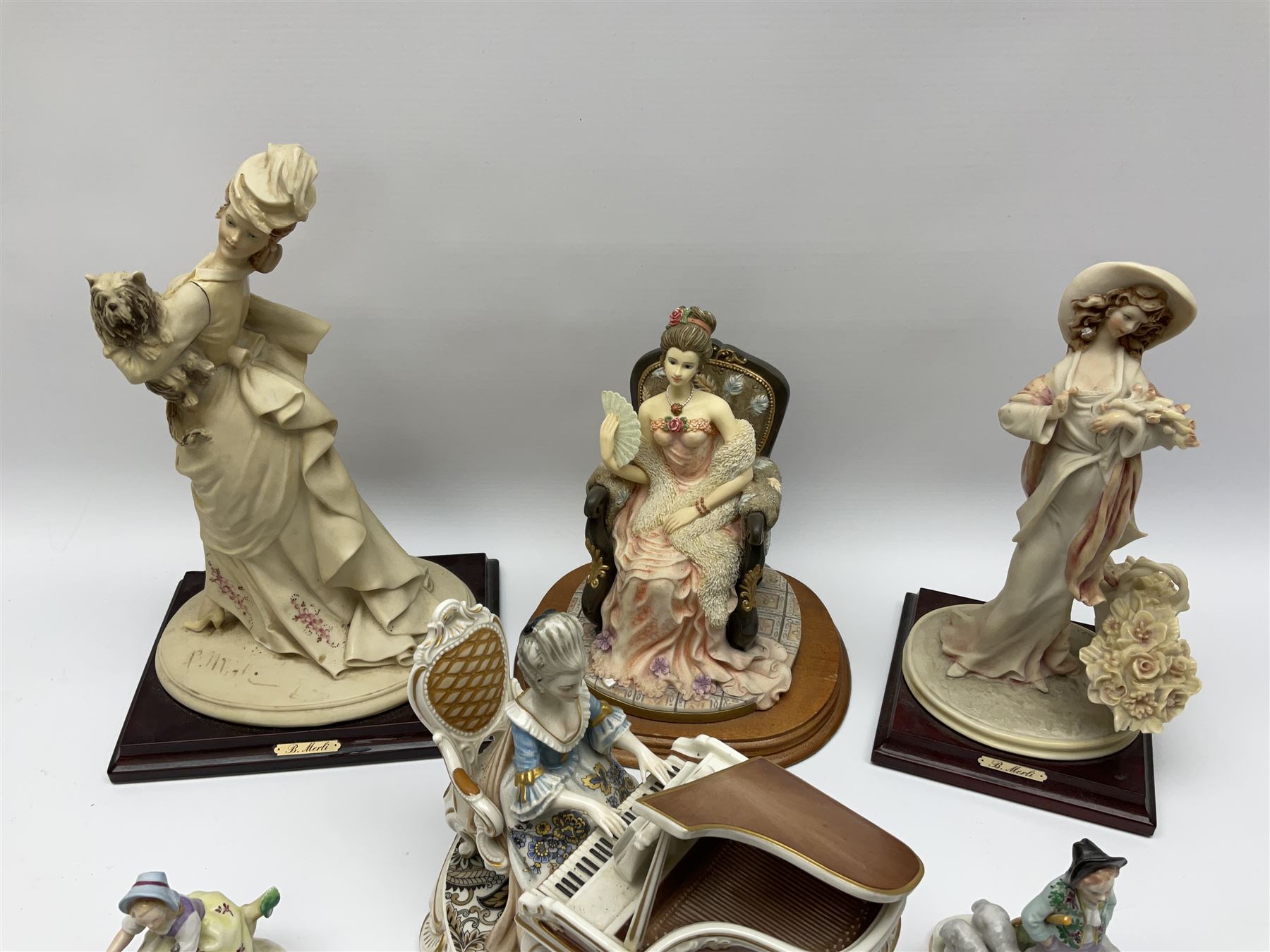 A small pair of Sitzendorf figures modelled as shepherd and shepherdess, H10.5cm together with a Dresden porcelain figure modelled as a female figure playing the piano, H17cm, a Naples figure with floral bouquet, H27.5cm,  a Naples figure holding a dog, H33cm, and a Leonardo Collection figure, Interlude, H24cm. 