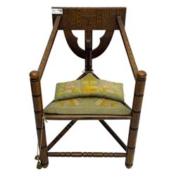 19th century swedish monk's chair, the oak frame with triangular seat and sloped arms, the backrest carved with geometric chipwork and a central pierced medallion 