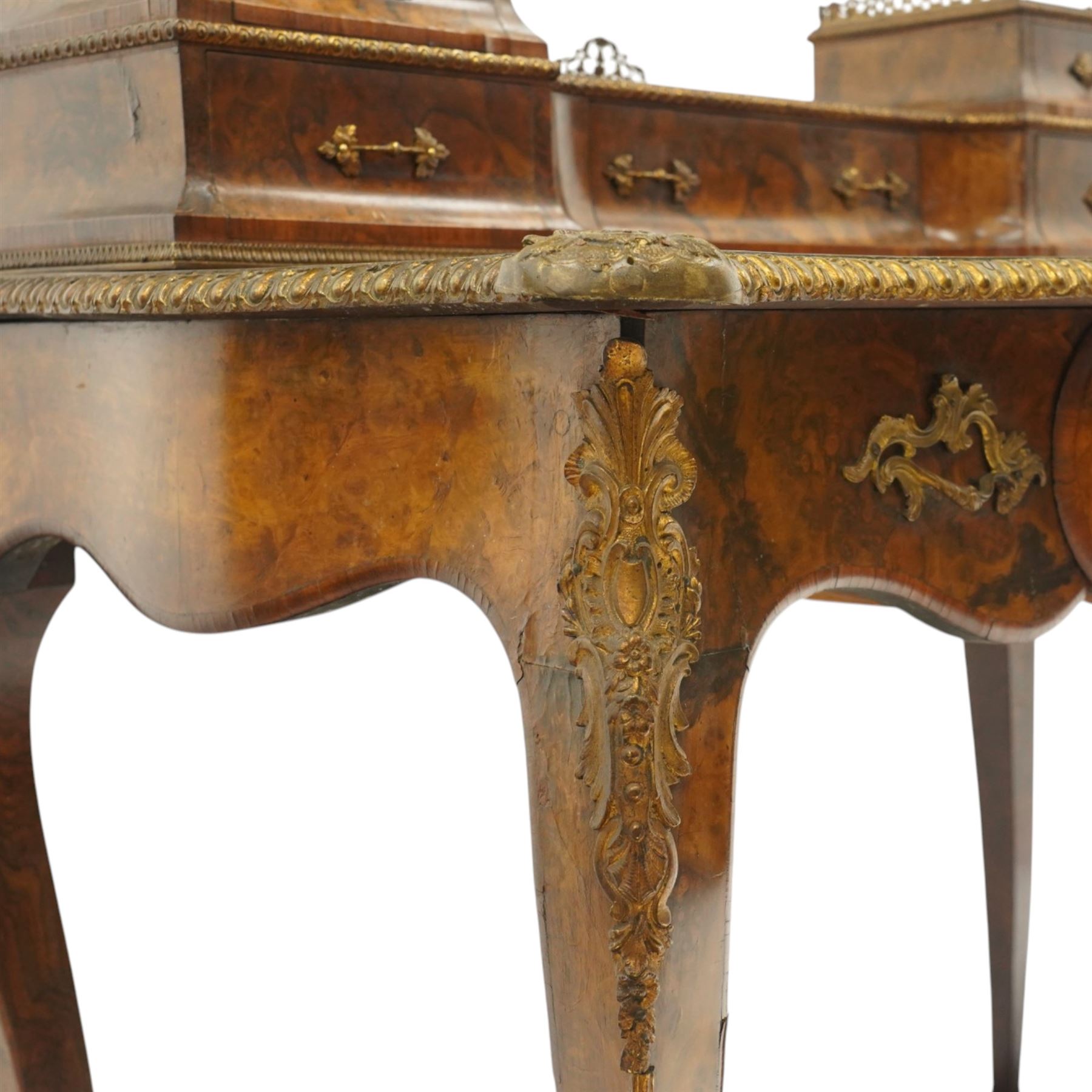 Victorian figured walnut and kingwood-banded ladies writing table, the raised superstructure with three-quarter pierced brass raised gallery back, fitted with five assorted drawers, the serpentine shaped top with oval inset leather surface, the bronze edge of egg and dart form with cartouche corners, fitted with central frieze drawer with inset Sevres-style floral ceramic plaque, raised on cabriole supports with gilt metal mounts