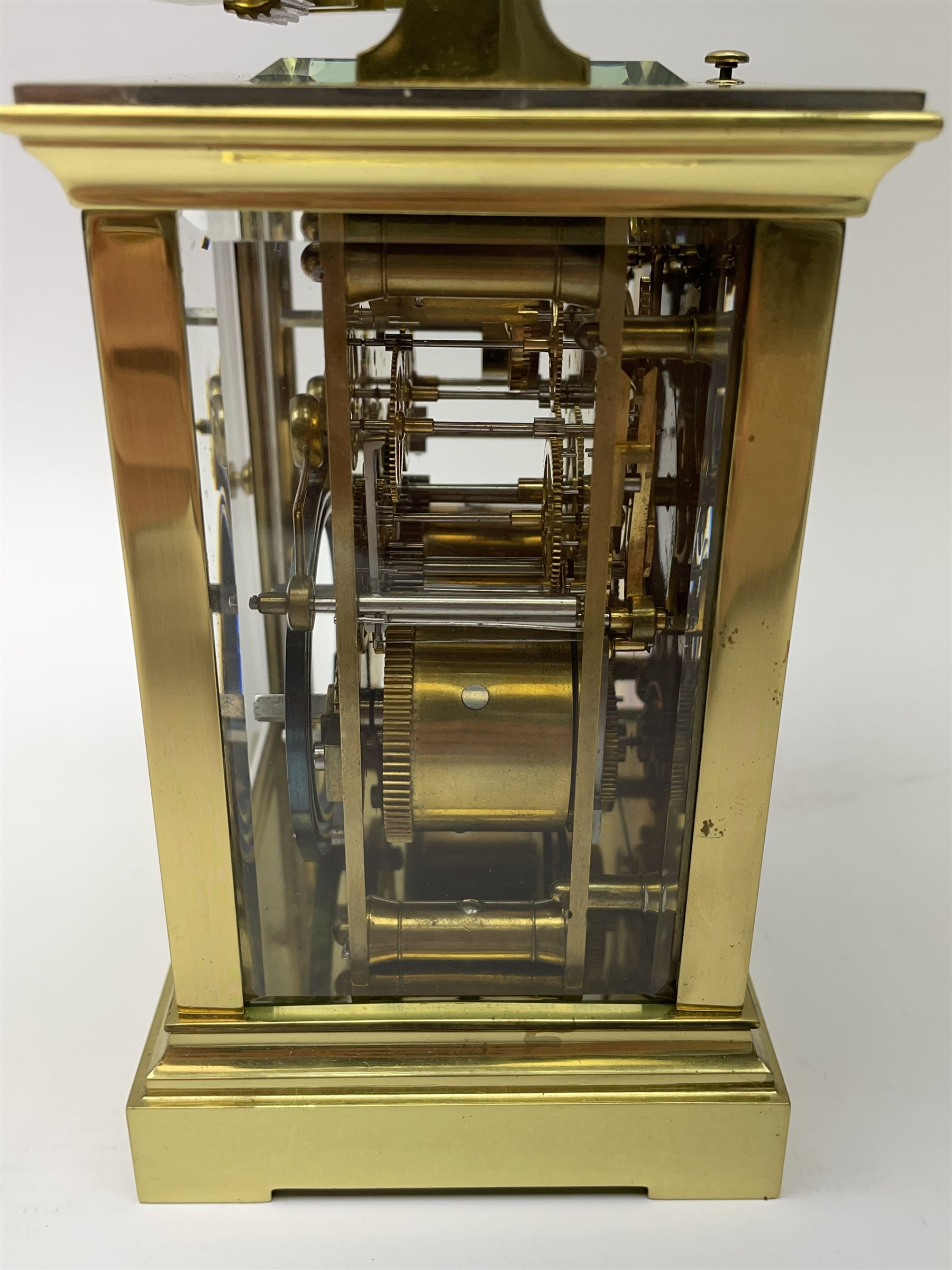 Early 20th century brass and bevelled glass repeater carriage clock with alarm, the angular and cylindrical ribbed handle and repeater button over stepped cavetto cornice, white enamel Roman dial with Arabic subsidiary alarm set dial, twin train eight day movement striking the hours and half on coil, separate alarm mechanism train, stepped moulded and plain faced base, with leather travelling case