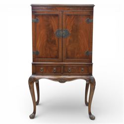 20th century Queen Anne style mahogany cocktail cabinet, moulded cornice above a pair of fielded panel doors with decorative strap hinges and central escutcheon, opening to a mirrored interior fitted with tiered shelves with brass gallery rails, pull-out glass inset mixing slide above three short drawers, shaped apron on cabriole supports with carved shell knees terminating in pad feet
