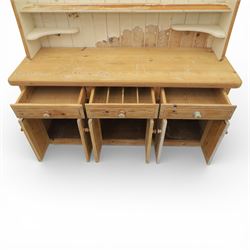 Late 20th century pine and white painted dresser, the upper section with three shelves and boarded back, upon a base with three drawers with knob handles and three panelled cupboard doors, on a raised sled base