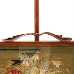 Two Victorian fire screens, comprising mahogany pole screen with glazed floral woolwork panel on turned support and triform base (H 142cm, W 48cm); and a larger carved walnut tapestry fire screen, glazed panel depicting a domestic interior scene, scroll carved cresting, barley twist uprights and turned stretcher base (H 75cm, W 49cm)