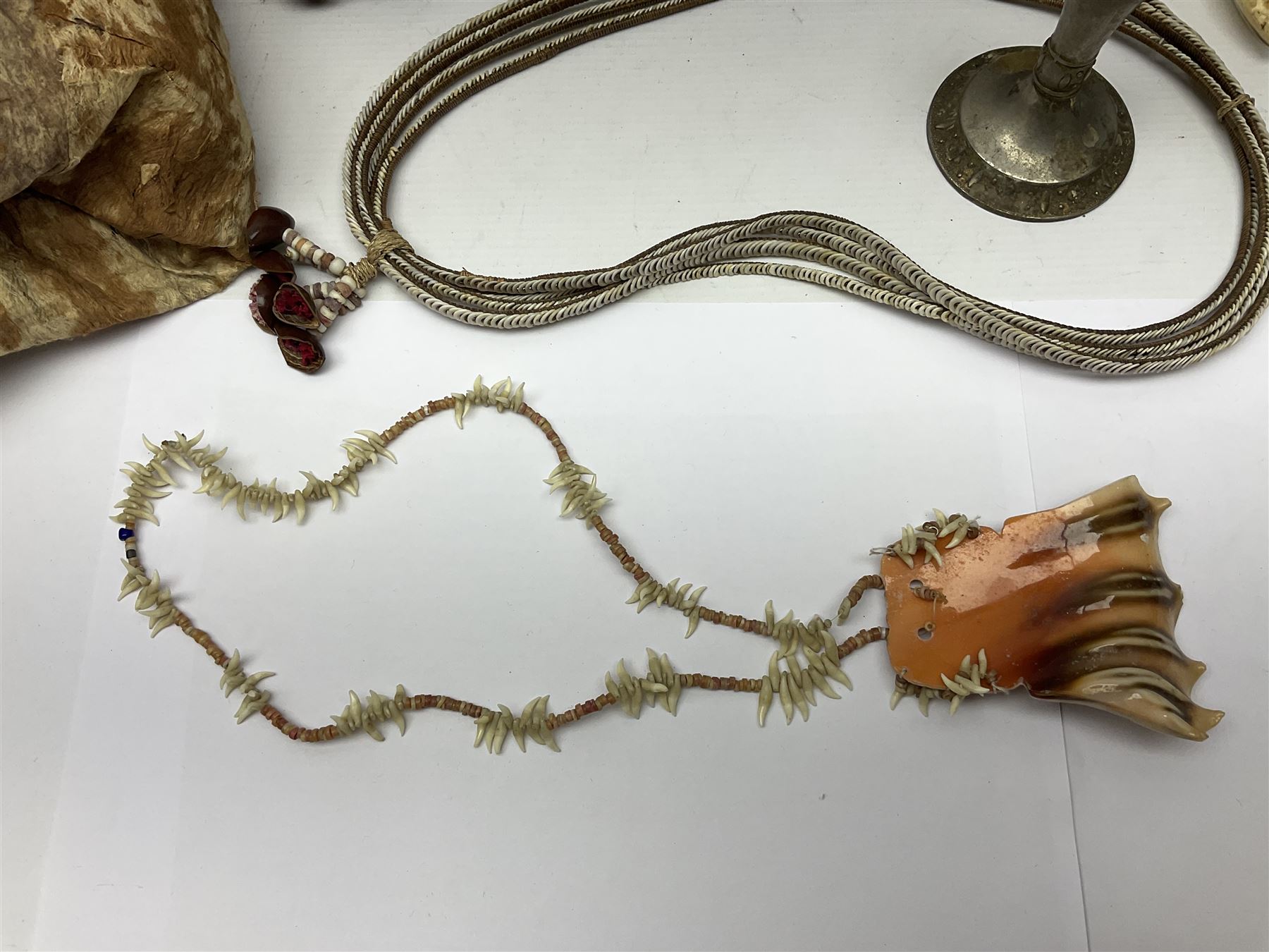 Collection of traditional necklaces from the Solomon Islands, including shell and boar tusk examples, together with a carved canoe prow, with mother of pearl eyes, painted cow hide and a copper plaque, depicting the Solomon Islands, with presentation engraving