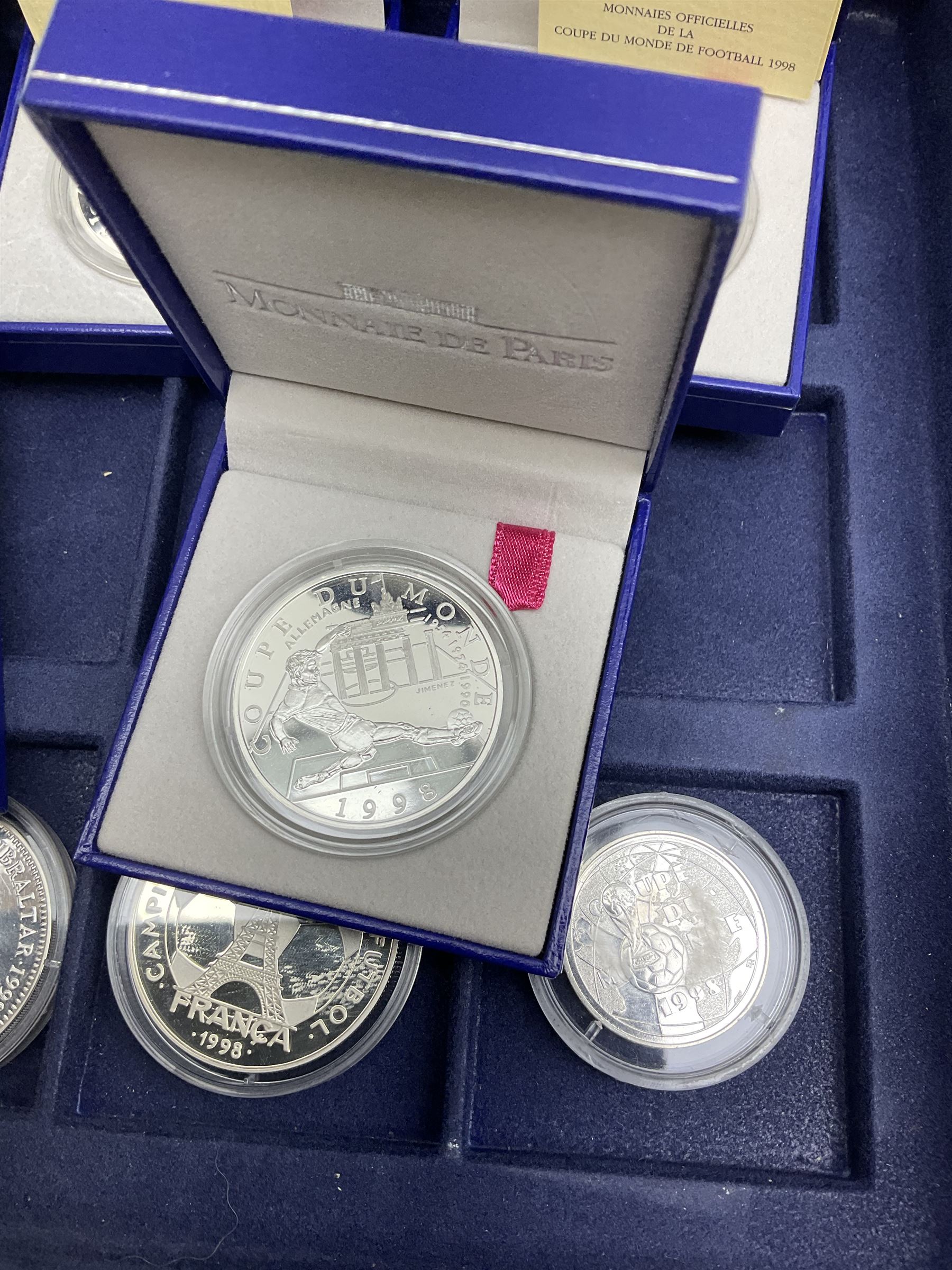 Nine commemorative coins relating to the France 1998 World Cup, some cased with certificates, in a blue coin storage box