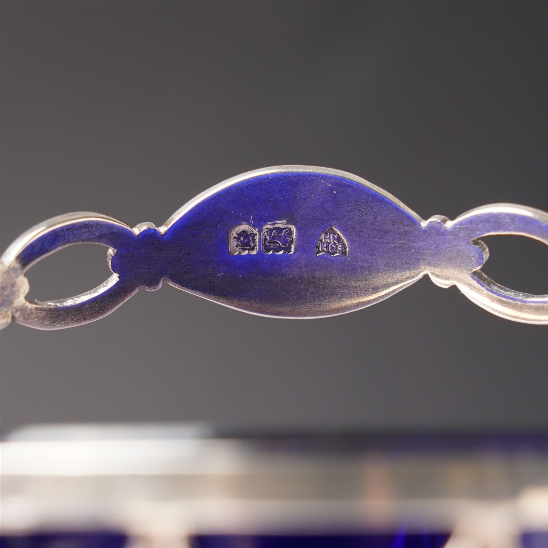 Edwardian pierced silver sugar basket with swing handle and blue glass liner H9cm London 1906 Maker Haseler Bros. and another decorated with floral swags Chester 1912 Maker  (2)