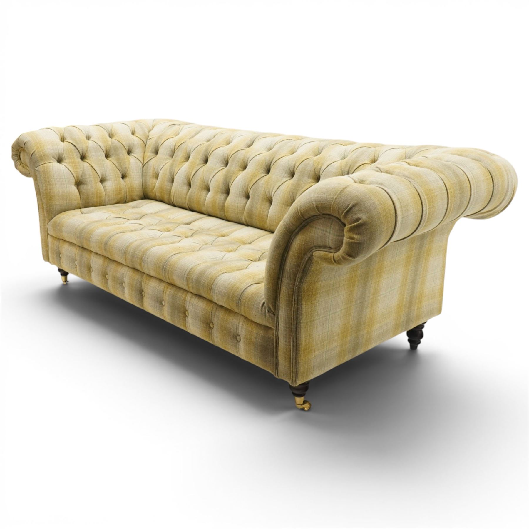 Late 20th century Chesterfield style two seat sofa, upholstered in muted green and yellow tartan fabric with buttoned back, arms and seat, on turned front supports with brass castors