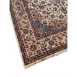 Persian Najafabad ivory and peach ground rug, central rosette medallion surrounded by swirling leafy branches and palmettes, trailing border decorated with stylised plant motifs, enclosed within floral pattern guard stripes