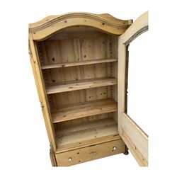 Late 19th century Continental pine vitrine, shaped and moulded arched cornice over a single glazed door enclosing adjustable shelves, flanked by carved pilasters with foliate and geometric motifs, fitted with single moulded drawer, raised on compressed bun feet