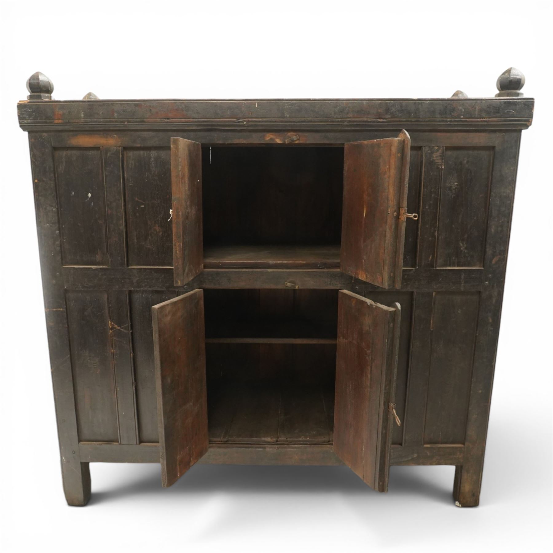 19th century oak hutch cupboard, plank top with moulded cornice and turned finials, panelled front enclosed by two tiers of central double doors with iron hinges and wooden latches, flanked by fixed fielded panels, on stile supports