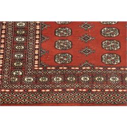Turkoman hand-knotted rug, madder red ground with two rows of repeating octagonal guls interspersed with geometric motifs, enclosed by multiple geometric and stylised floral borders, with fringed ends