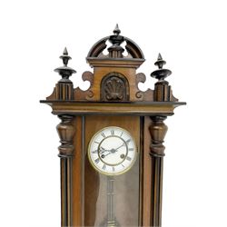 German - late19th century walnut and ebonised Vienna style wall clock, with a carved pediment and finials, fully glazed door flanked by two reeded pilasters, visible gridiron pendulum with beat plate, pierced steel hands and a two part enamel dial, twin train going barrel movement striking the hours and half hours on a coiled gong. With key.
