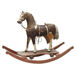  19th/ early 20th century pull-along horse, pony-skin covered wooden frame with glass eyes and leather bridle on rectangular stained pine base with four cast metal wheels, later converted to a rocking horse, H85cm x L115cm   