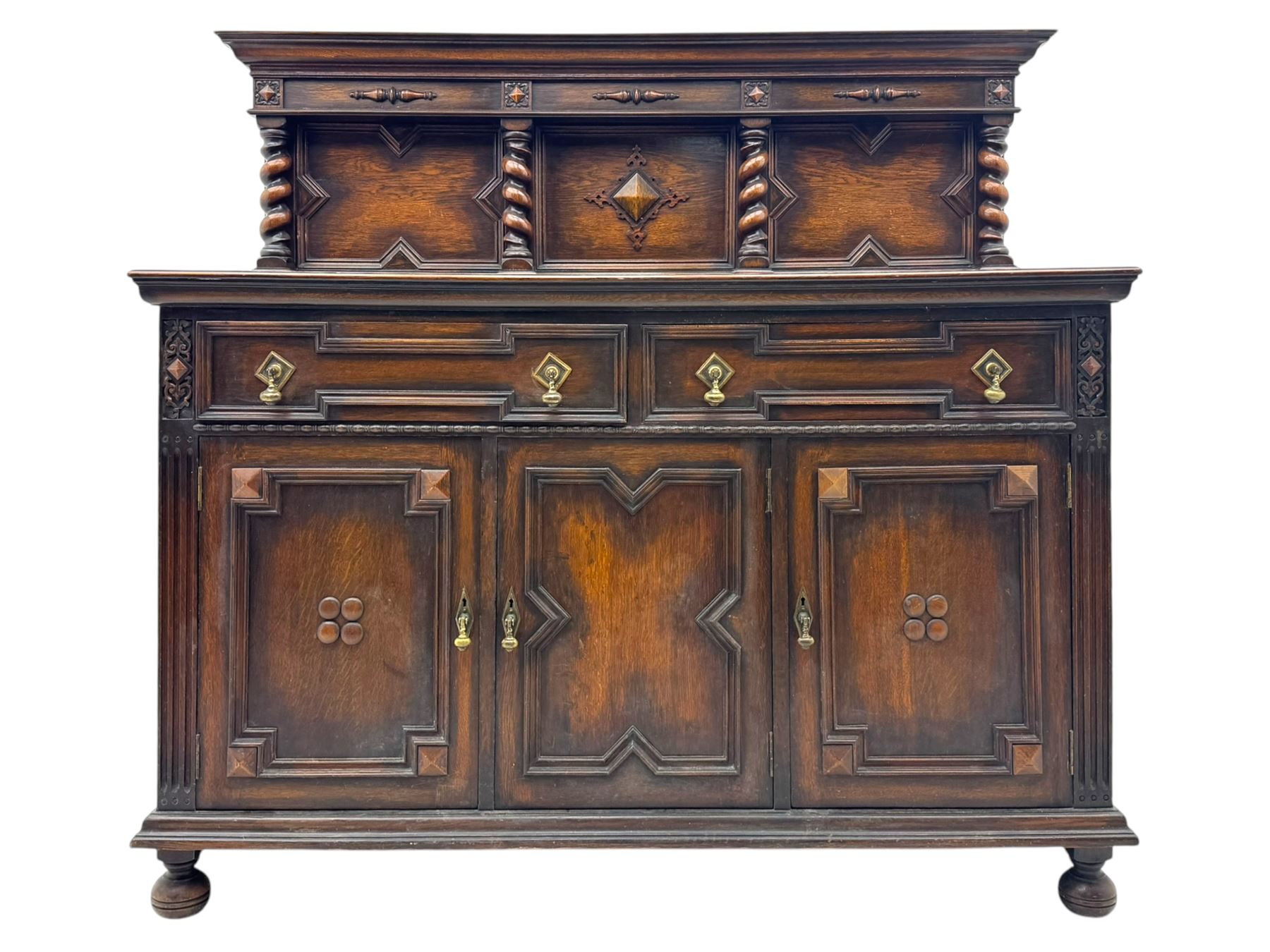 Jacobean-style oak dresser base with two frieze drawers above three cupboards with panelled and moulded decoration, fitted with drop handles, supported on bun feet, circa 1900