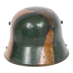 WWI German camouflage M17 helmet, with camouflage painted finish to the skull in green, brown and ochre colours with black separation lines, the interior with leather band which supports three pad leather lining, the pads stamped with indistinct marks 