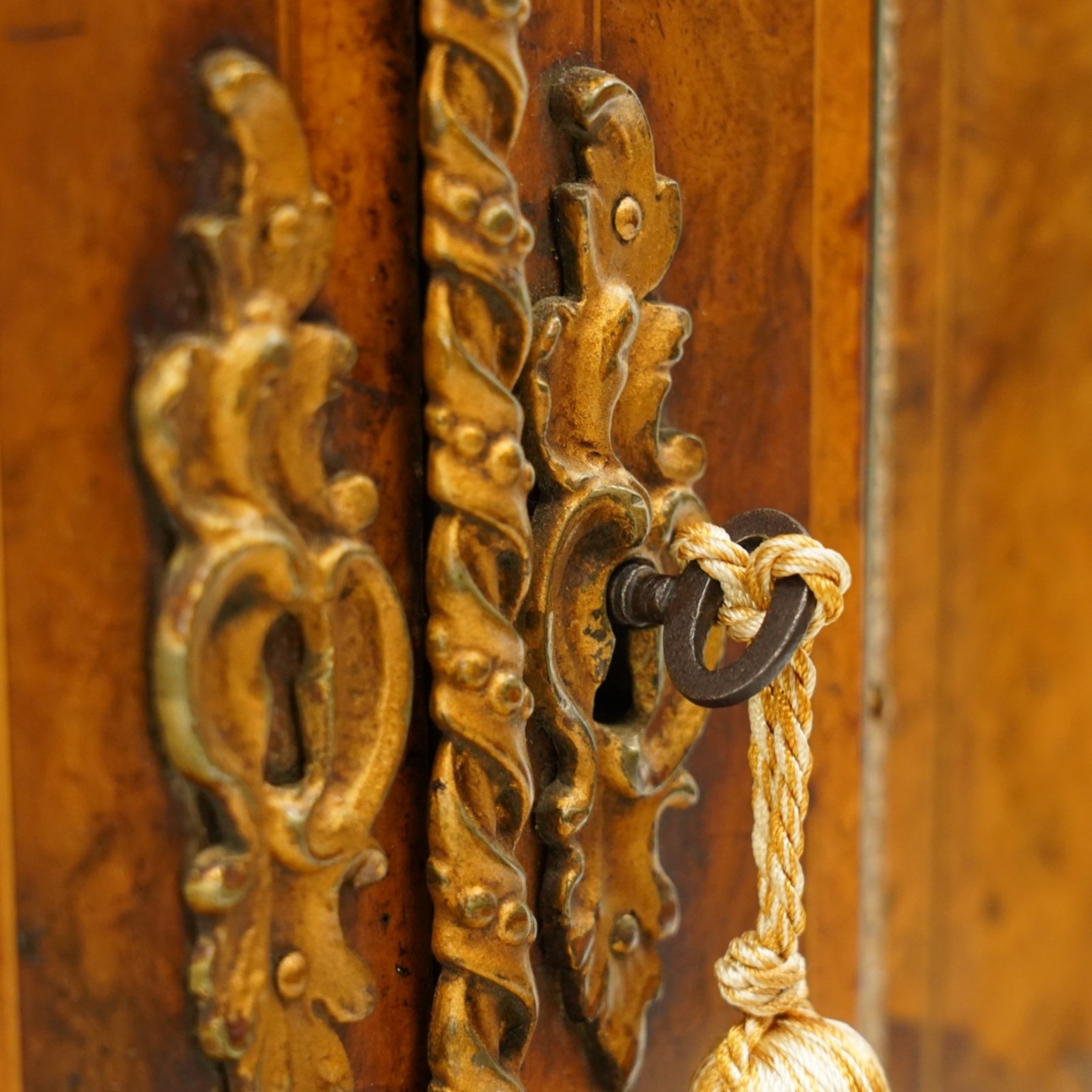 Large fine Victorian figured and burr walnut credenza, the breakfront D-shaped top with moulded edge, over an ornate frieze with inlaid Aesthetic Movement scrolling and geometric ornament, applied with gilt-metal ribbon-twist moulding and mounts, the central panelled doors profusely inlaid with scrolling foliate motifs and stringing, flanked by gilt-metal cartouche and scrolling acanthus corbel mounts, with flanking glazed bow-front side doors, on skirted base with further gilt metal foliate mounts