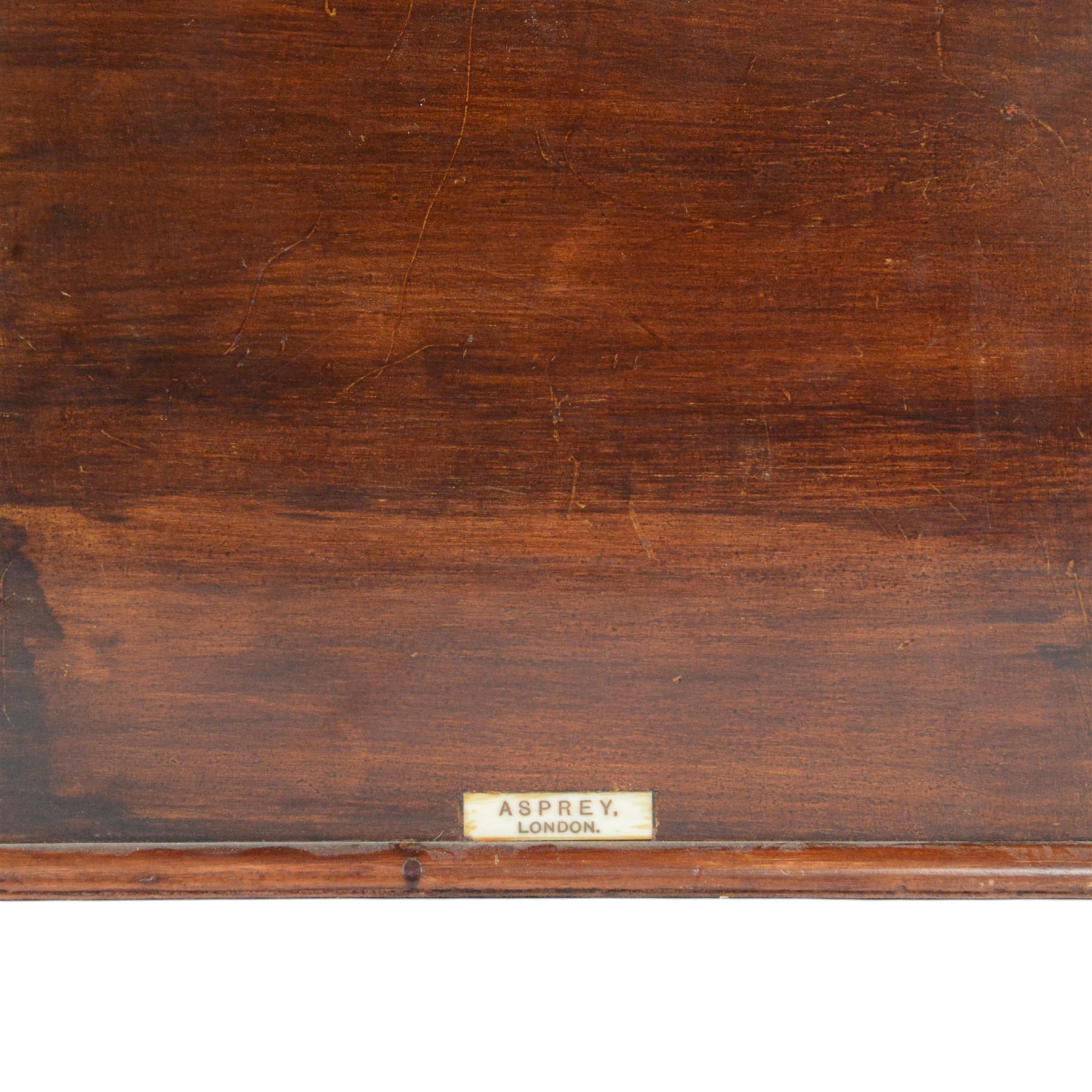 Edwardian Asprey mahogany desktop book trough, the segmental arched back with inlaid fan patera and serpentine shaped sides, above single recess and moulded base rail, housing Asprey & Co Ltd leather bound reference library, comprising Dictionary, French and English Dictionary, English Quotations and Proverbs, Classics and Mythology, Encyclopedia, French and Latin Quotations, Gazetteer, and Atlas, book trough, 22cm x 22.5cm x 11cm
