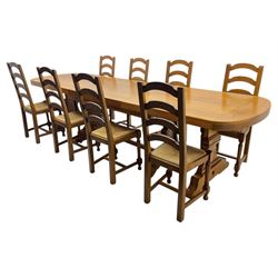 Oak extending dining table with elegant scrolled shaped double pedestal base and scrolled feet; together with a set of eight ladder back chairs with rush seats ((9) table closed 228x95x79cm chairs 106x38x44cm 