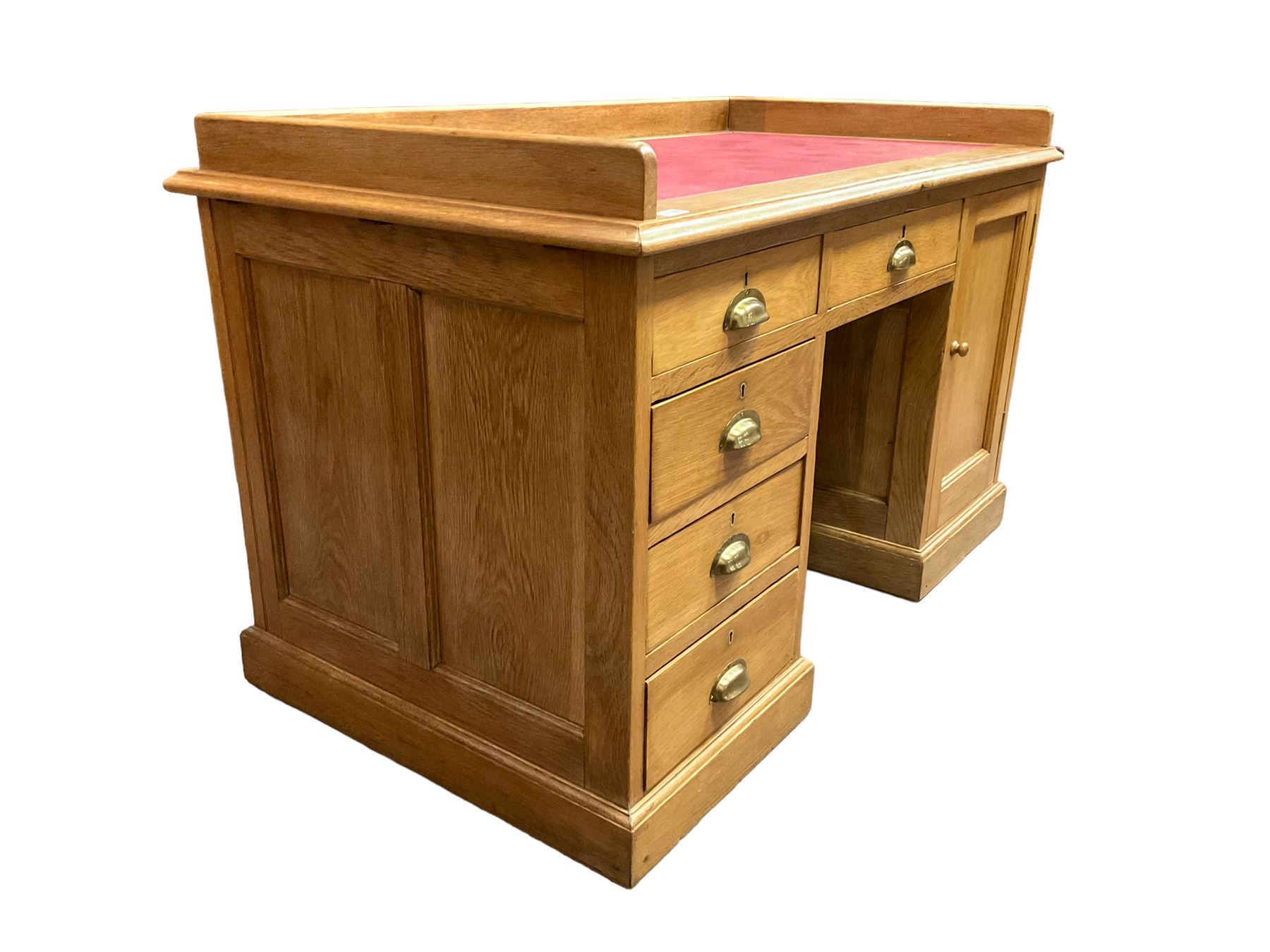 Early 20th century oak ‘Headmasters’ twin pedestal desk, three-quarter raised gallery back and inset leather writing surface, fitted with central drawer flanked by four graduating drawers and single cupboard