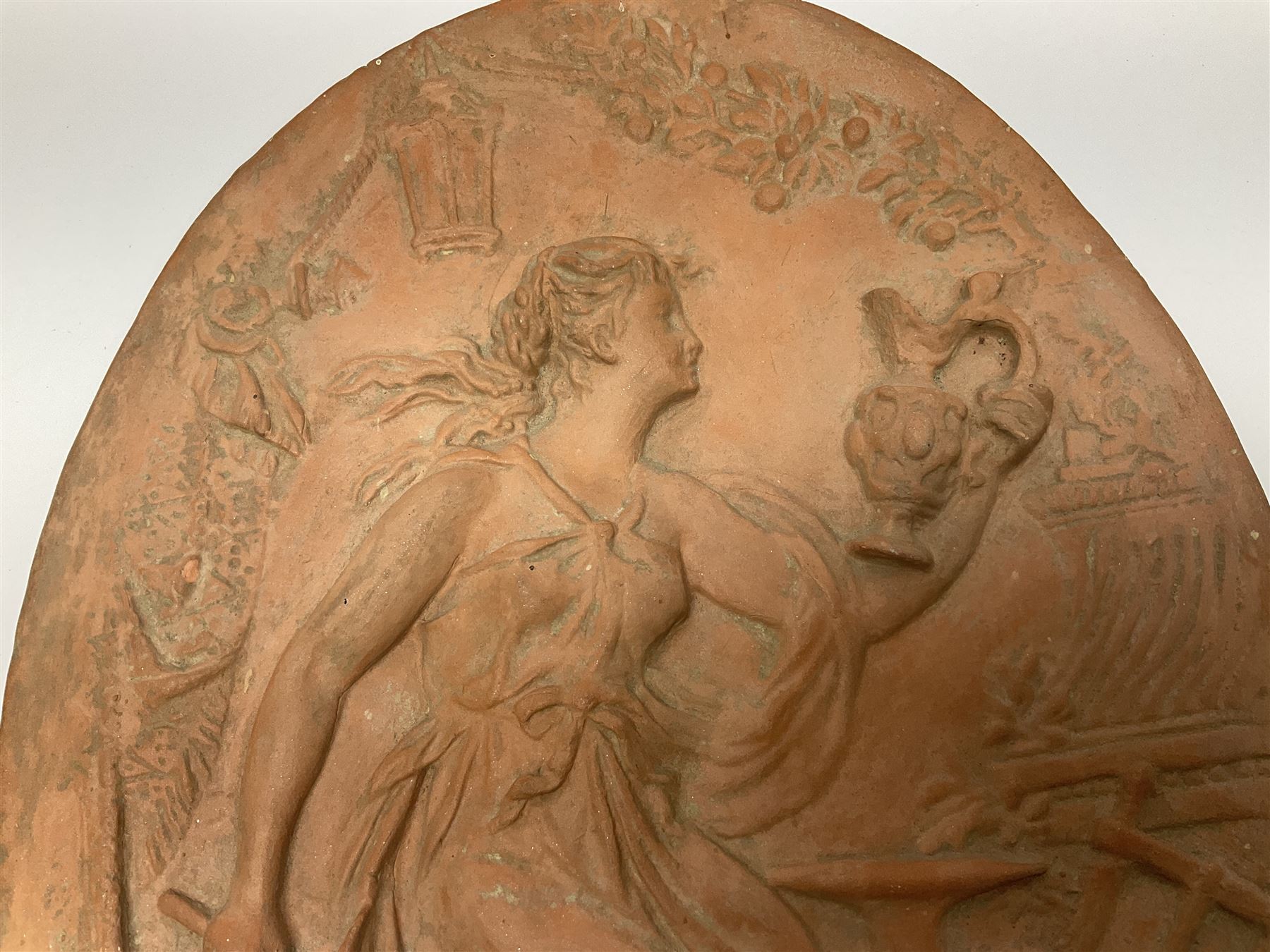 Pair of 19th century classical terracotta relief wall plaques depicting the goddess Hygeia and another goddess, seated holding an ewer, each of oval form, indistinctly signed, each stamped Ferreira verso, H42cm, W30cm