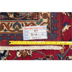 Central Persian Kashan hand-knotted carpet, rose red field, with central shaped lobed medallion issuing an all-over scrolling design of palmettes, floral sprays and arabesques, within conforming spandrels, enclosed by a broad indigo herati type palmette border framed by multiple guard stripes, in a palette of deep red, midnight blue and ivory tones, with cotton fringe ends, and Kashan signature 