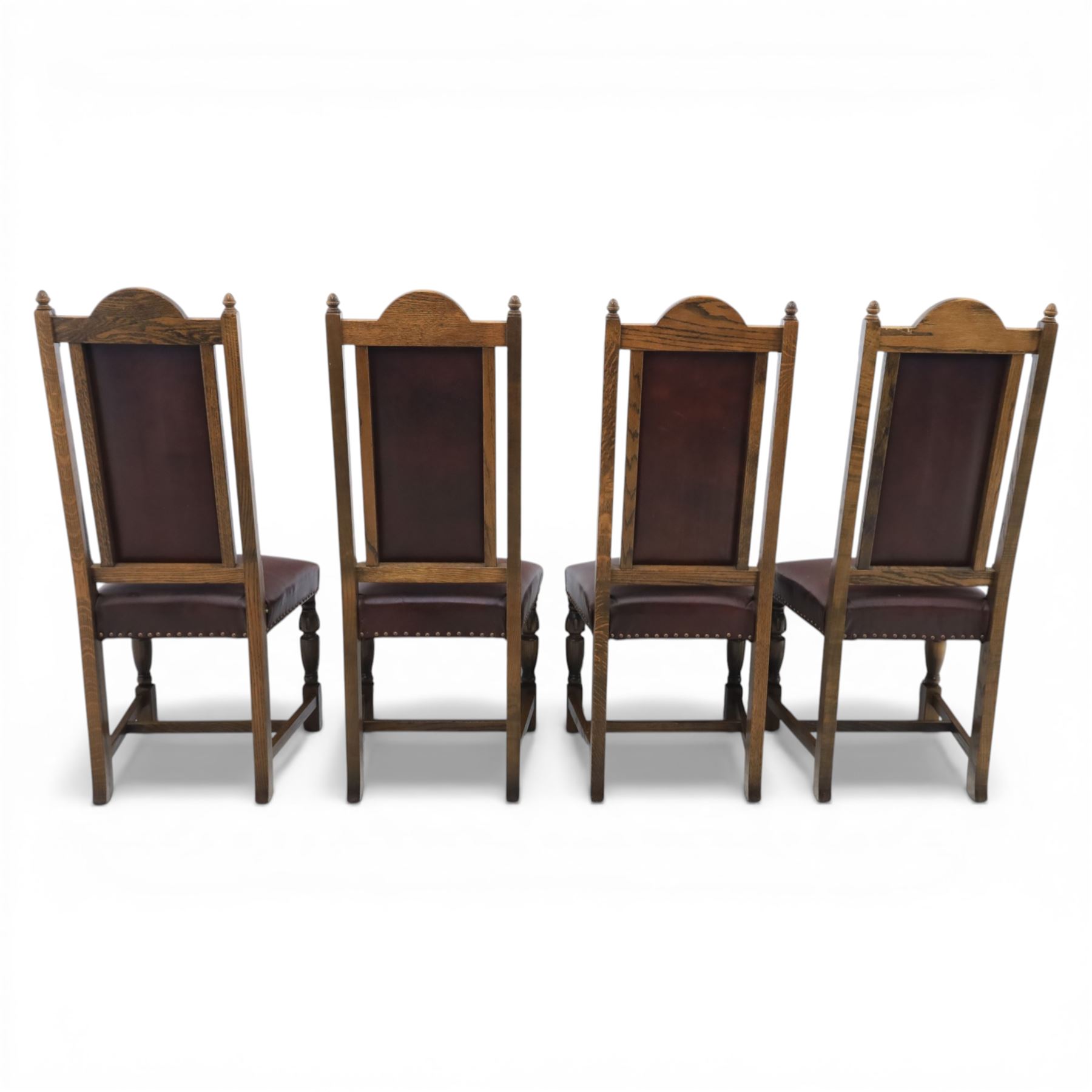 Carolean revival oak dining table and eight chairs (7+1), refectory table with rectangular boarded top and cleated ends, raised on shaped trestle end supports with central stretcher, accompanied by eight high-back chairs including a carver, leather upholstered panels and seats with studwork, on turned legs with stretchers.