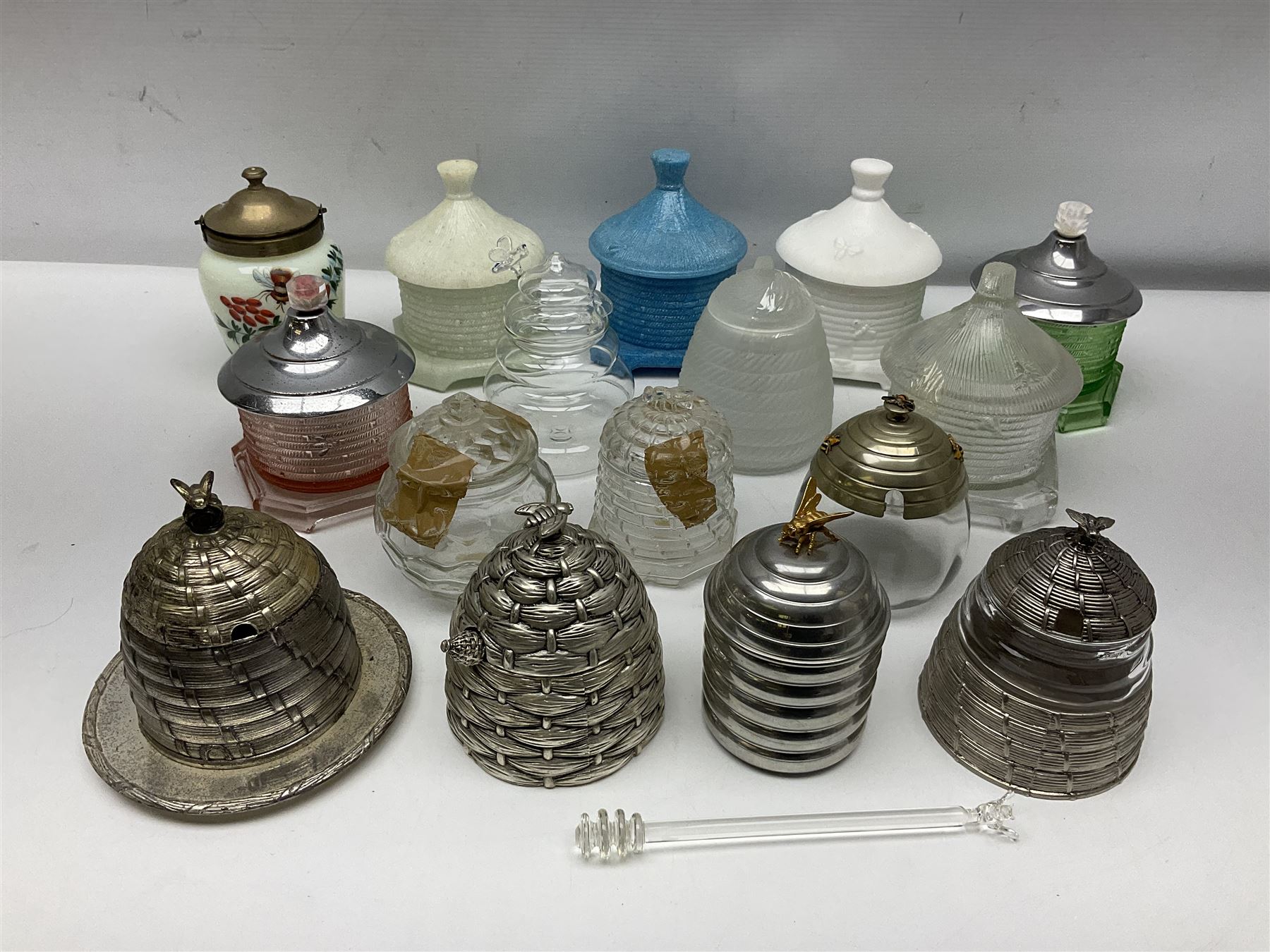 Collection of glass beehive honey pots, to include a blue slag example, milk glass, pink, green, etc together with four white metal examples (16) 