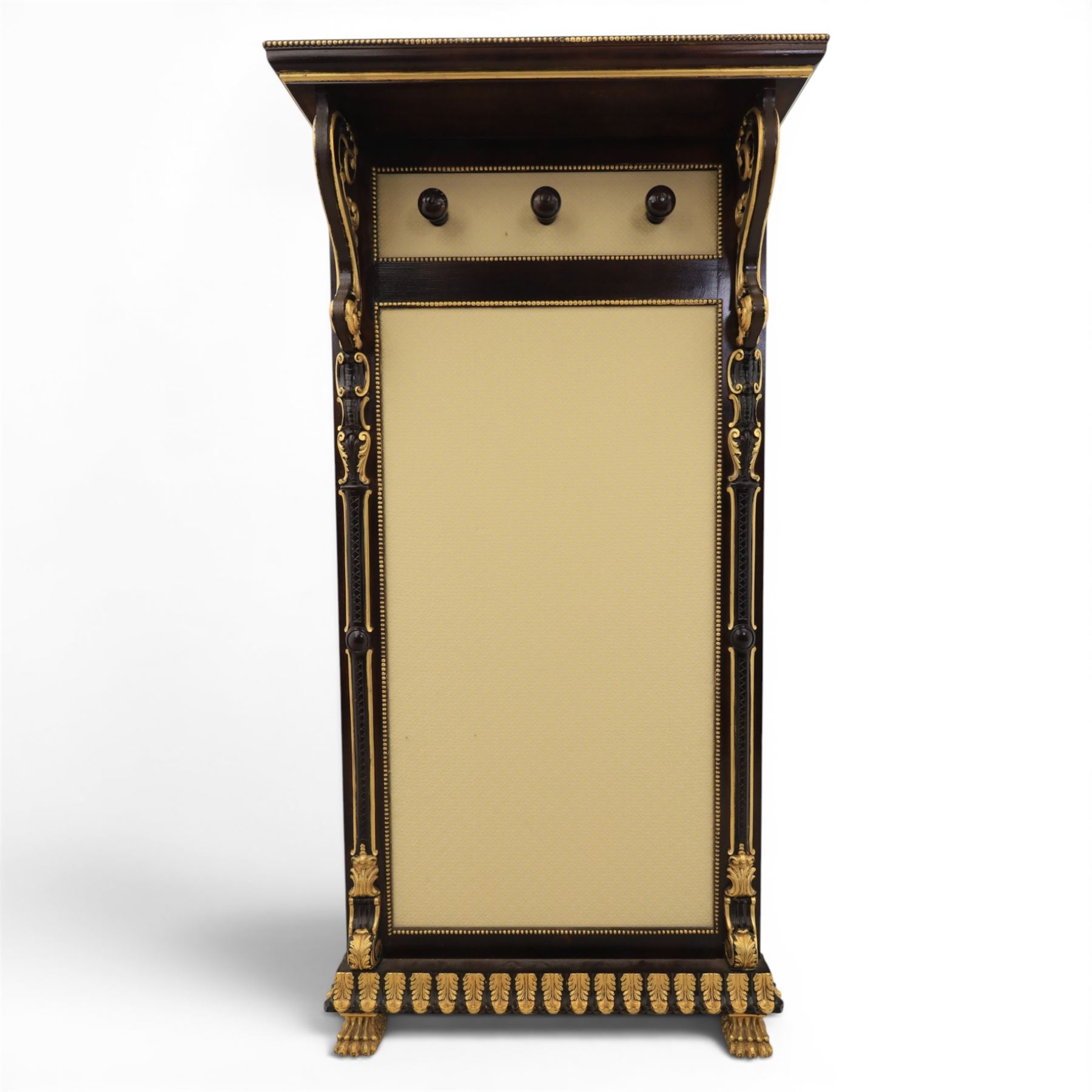 Empire design ebonised and parcel gilt hall stand, projecting moulded cornice with bead and reel border, upper rail fitted with three turned hat and coat pegs, central cream upholstered panel within beaded slip, flanked by scrolled uprights with gilt foliate and anthemion mounts, lower acanthus leaf apron, on paw feet