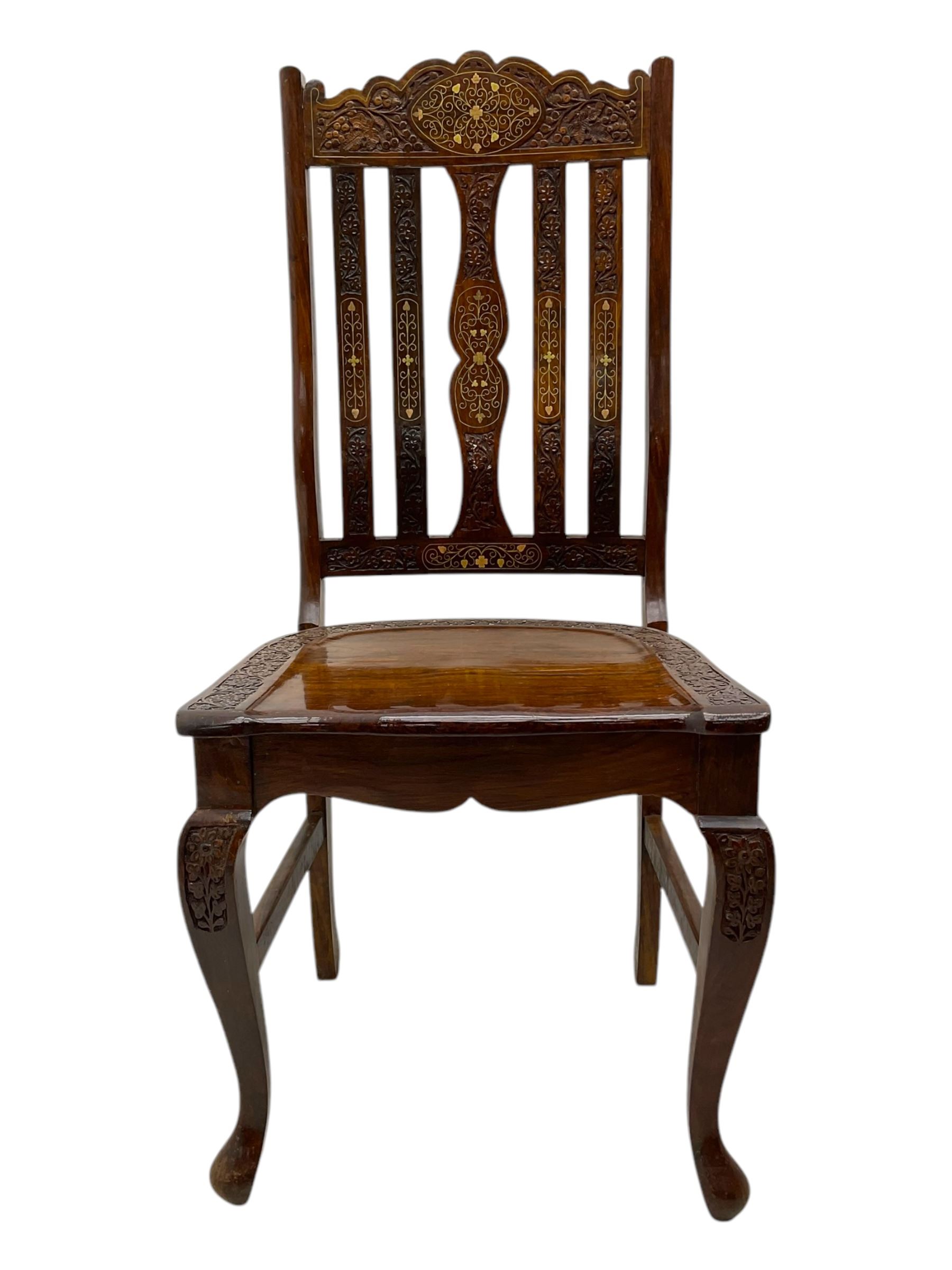 Pakistan carved hardwood brass inlaid circular dining table, and four rail back chairs with saddle seats