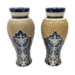 Pair of Royal Doulton Lambeth stoneware baluster vases, decorated in light relief with panels of foliage on blue ground, with gilt scrolls above, impressed mark beneath, 28cm high