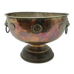 Copper pedestal punch bowl, with planished decoration with twin lion mask and ring handles and applied coins, H18cm