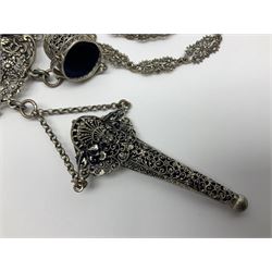 19th century continental silver plated chatelaine, the main body flanked with winged mythical beasts and central soldier slaying a dragon supporting three suspended items to include velvet lined small basket and long clasped filigree chain, together with a thimble