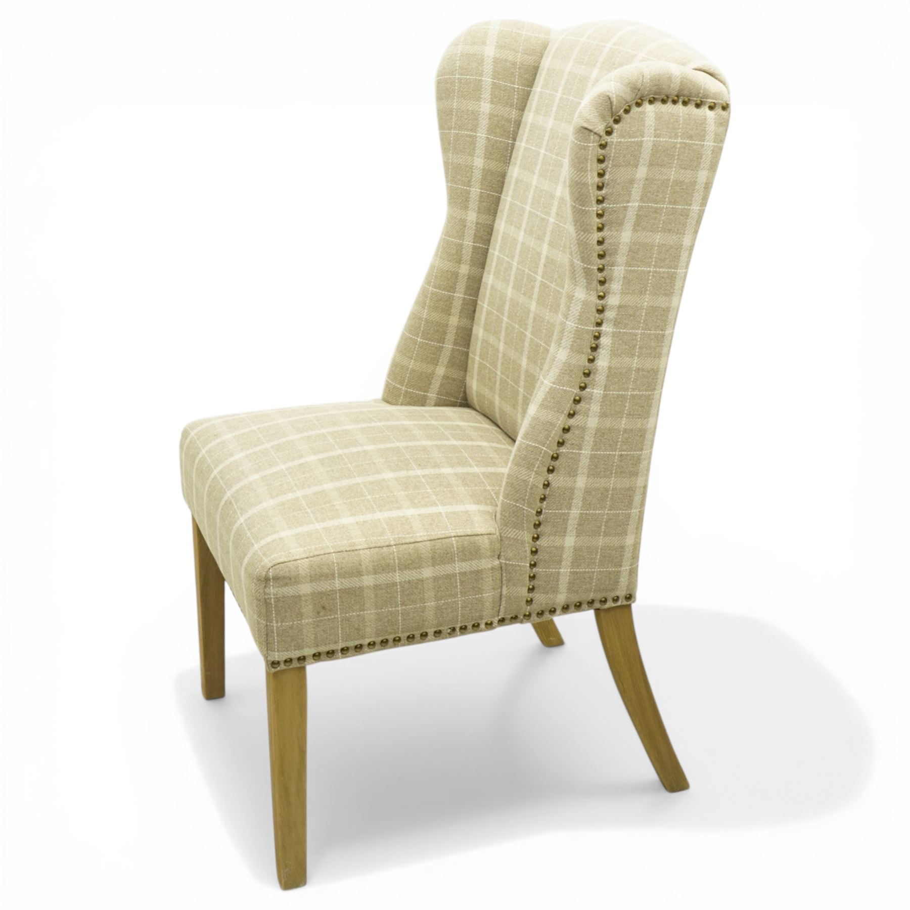 Contemporary wing back dining chair, fully upholstered in beige plaid fabric with studded edge detail, shaped back and seat, raised on tapering supports