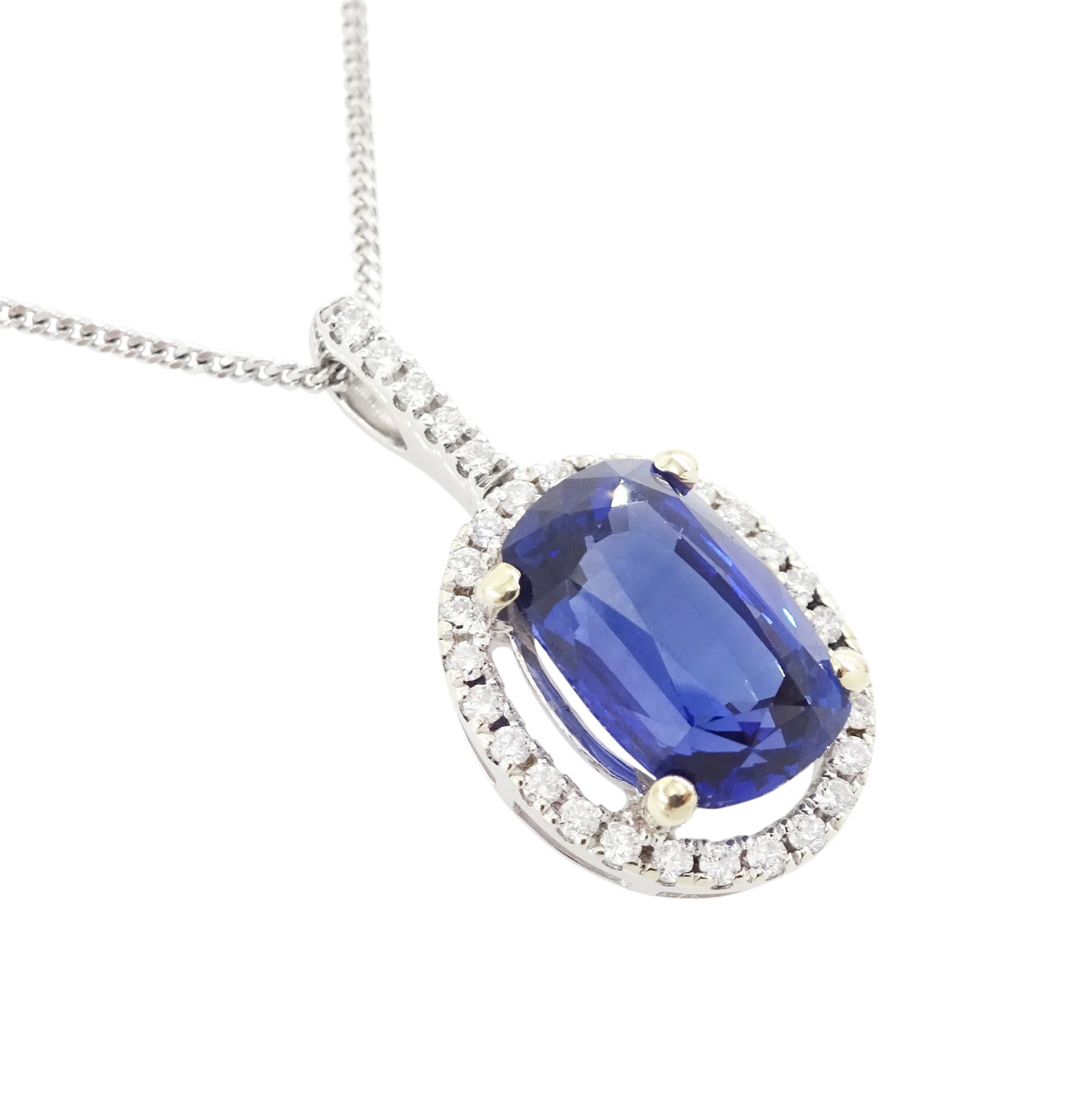 18ct white gold sapphire and diamond halo pendant necklace, single cushion cut sapphire of approx 4.65 carat, with round brilliant cut diamond surround and bail, on fine flattened curb link chain necklace, both hallmarked, total diamond weight approx 0.35 carat