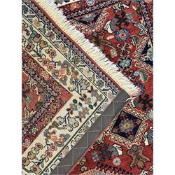 Pair of rugs one Persian hamadan rug central stepped medallion enclosing geometric motifs in ivory and brown, framed by a cream border with scrolling palmettes and fringed ends (H 156cm W 105cm), one Pakistani Bokhara rug rust red ground with repeated Tekke gul motifs within rosette and lozenged borders, fringed ends (H 98cm, W 65cm)